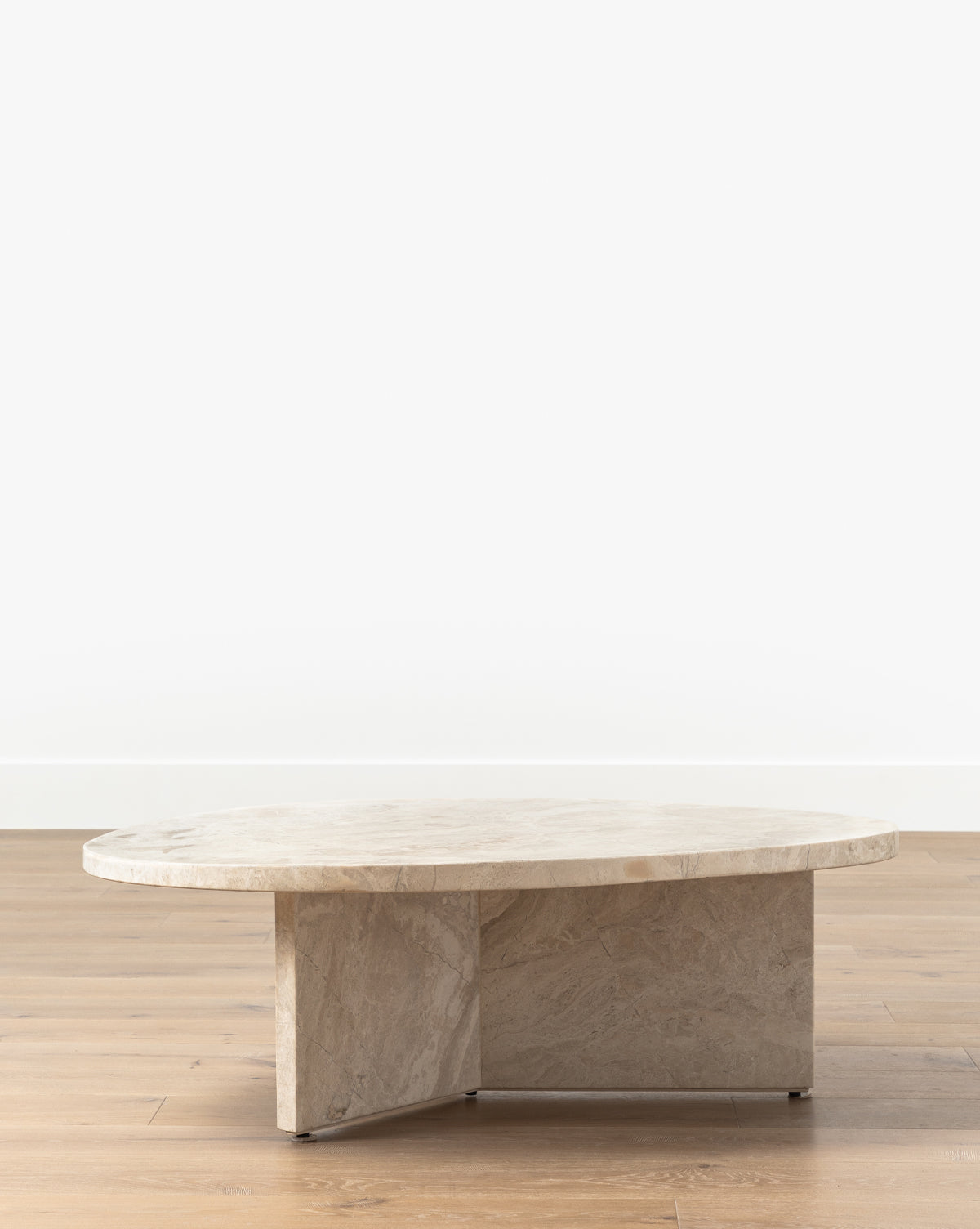 The Cassius Coffee Table boasts a round, thick Turkish Dyna Marble top and a solid intersecting base, creating a modern look ideal for placement on light wooden floors against white walls, by McGee & Co.