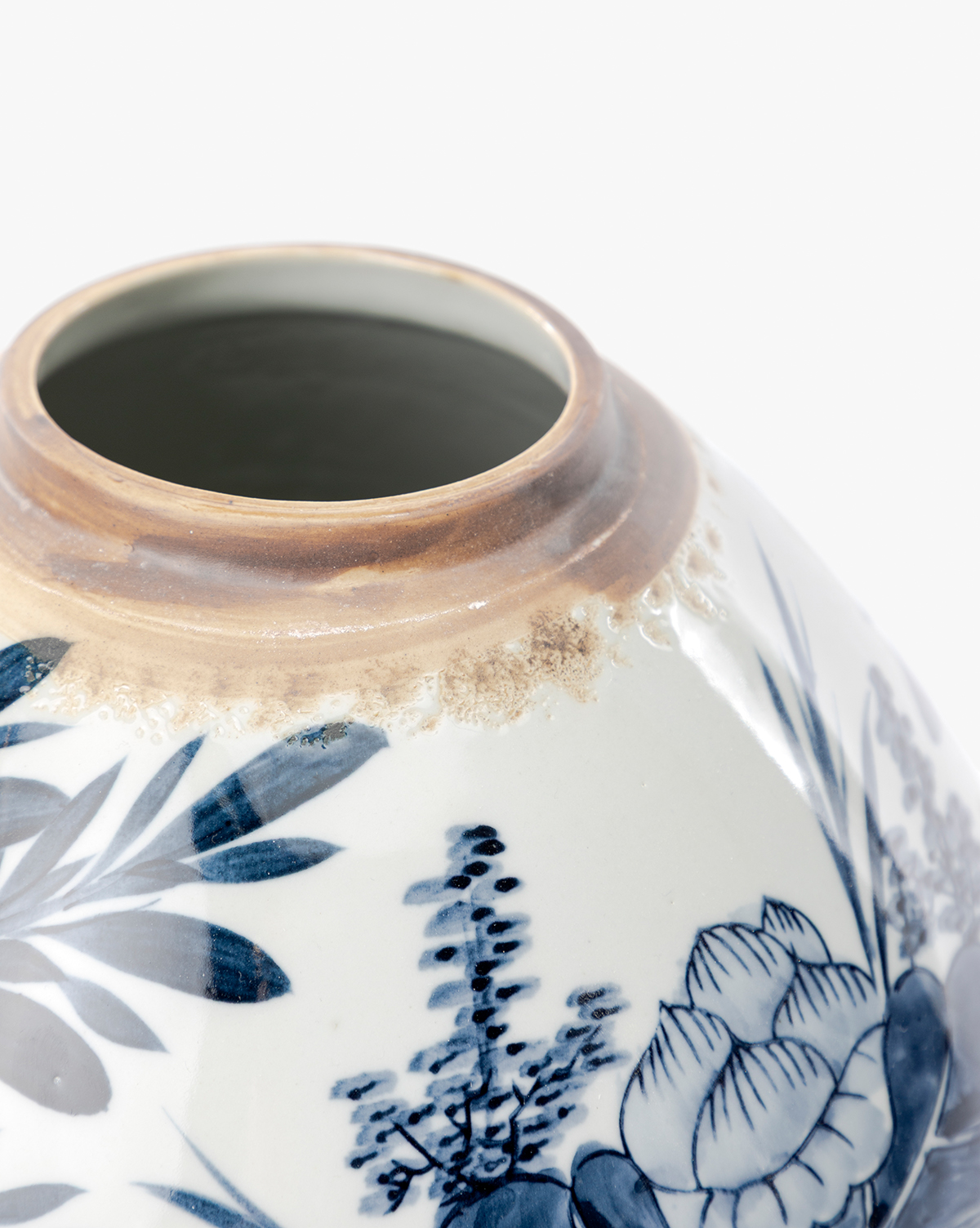 Close-up of the base of a Chinoiserie Ginger Jar with hand-painted blue and white floral patterns and brown discoloration near the rim, shown against a plain white background, by Vendixs