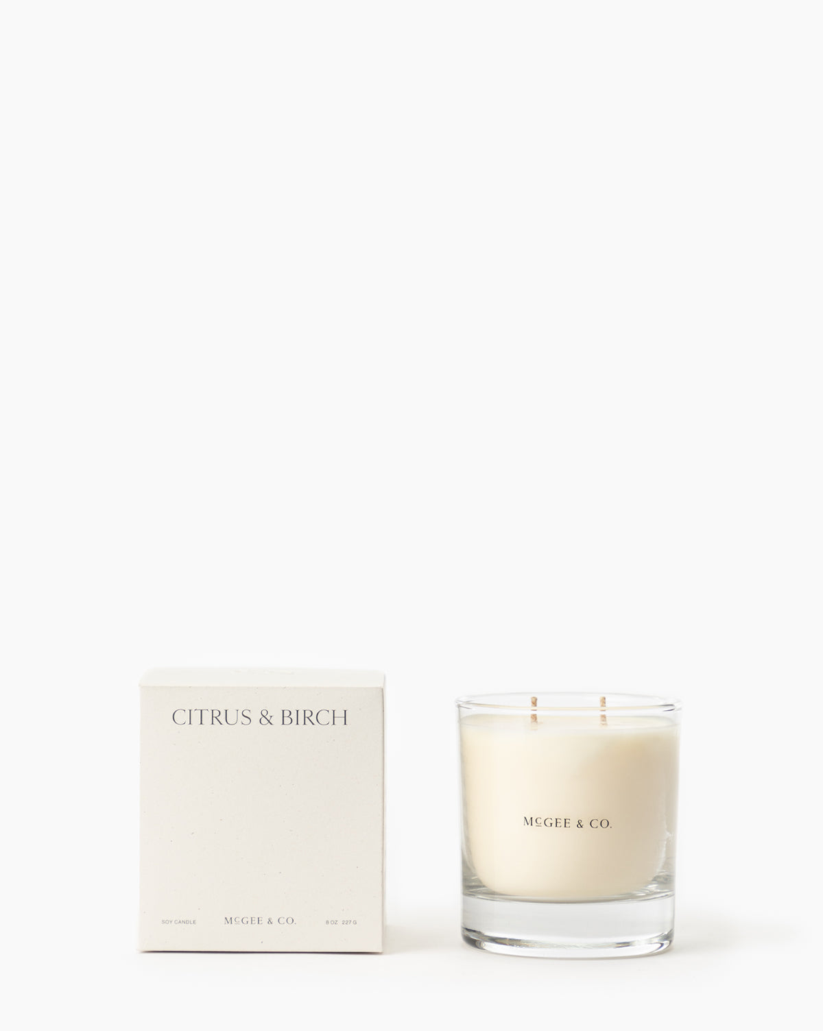 A white box labeled Citrus & Birch Candle sits beside a Vendixs luxury glass jar candle made from soy wax with two wicks, both displayed against a plain white background by McGee & Co.