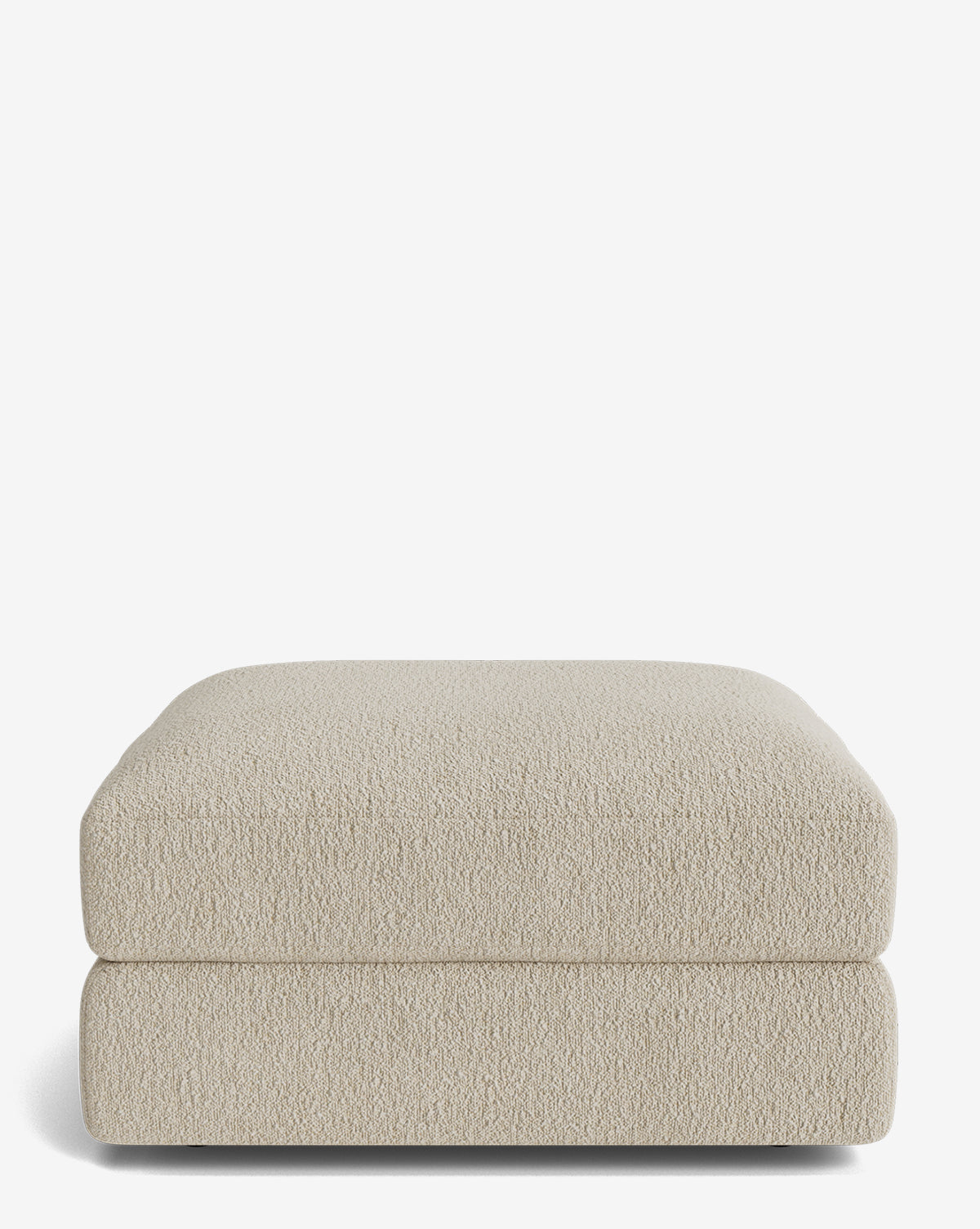 The Claremont Modular Ottoman by Makerspalm features rounded edges and textured light beige upholstery, set against a plain white background. Vendixs