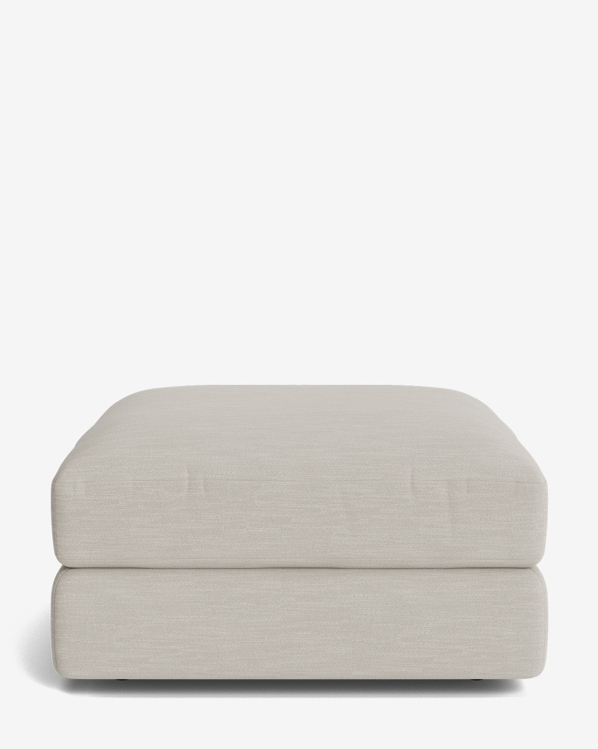The Claremont Modular Ottoman by Makerspalm is a large, square ottoman in light beige, featuring a simple modern design with soft, rounded edges, shown on a plain white background. Vendixs
