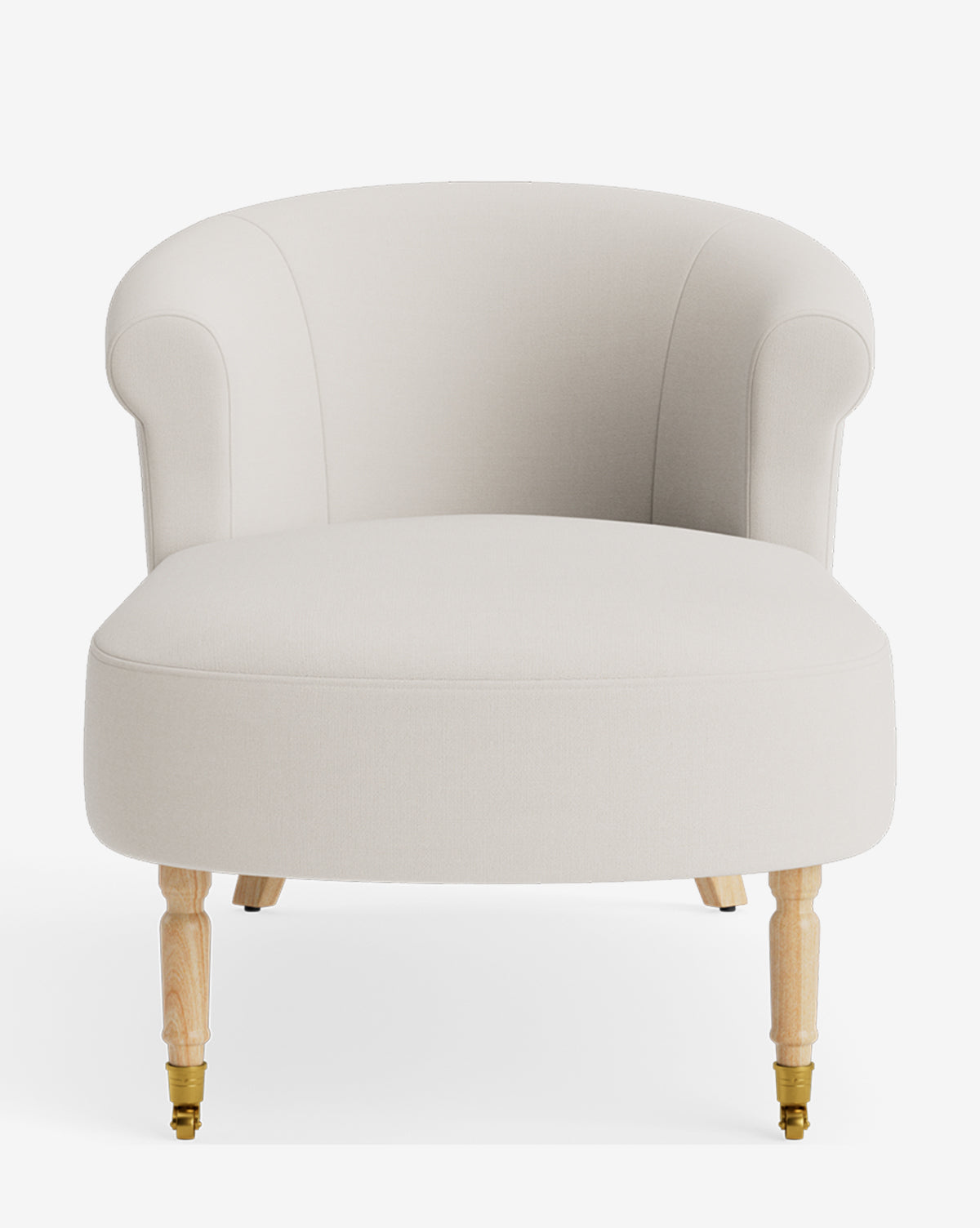The Clemence Chaise is an upholstered, cream-colored armchair with a rounded backrest, rolled arms, and light wooden legs. The front two legs have small brass castors. The chair is shown against a white background, by Vendixs
