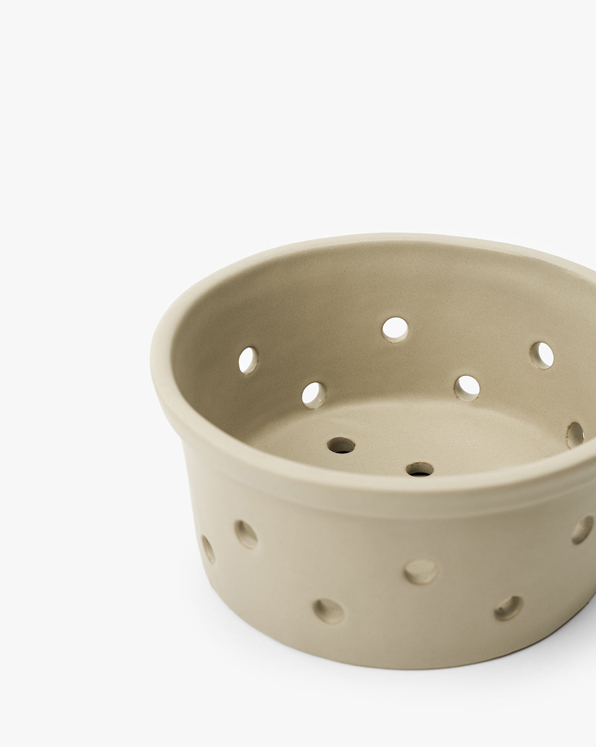 The Coen Berry Bowl, in beige with a matte finish and multiple round holes on its sides and bottom, is set against a white background by Vendixs
