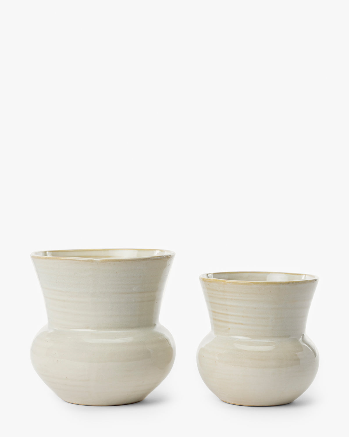 Two cream-colored Colchester Planters by Napa Home & Garden with a glossy finish, rounded base, and tapered rim are displayed side by side against a plain white background. Ideal as home decor or as ceramic planters. Vendixs