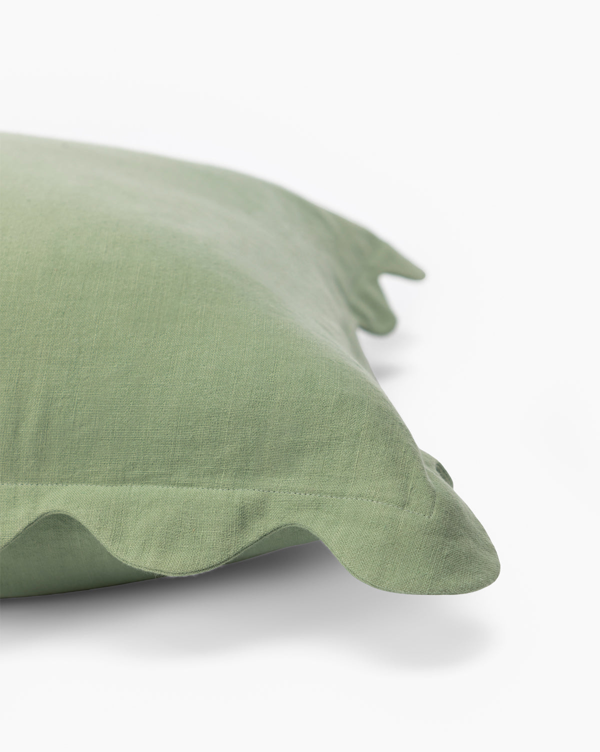 A close-up of the Vendixs x Loeffler Randall Colette Scallop Border Pillow Cover in pale green linen with a ruffled edge, shown on a white background—perfect for bringing chic style to your space, by Vendixs