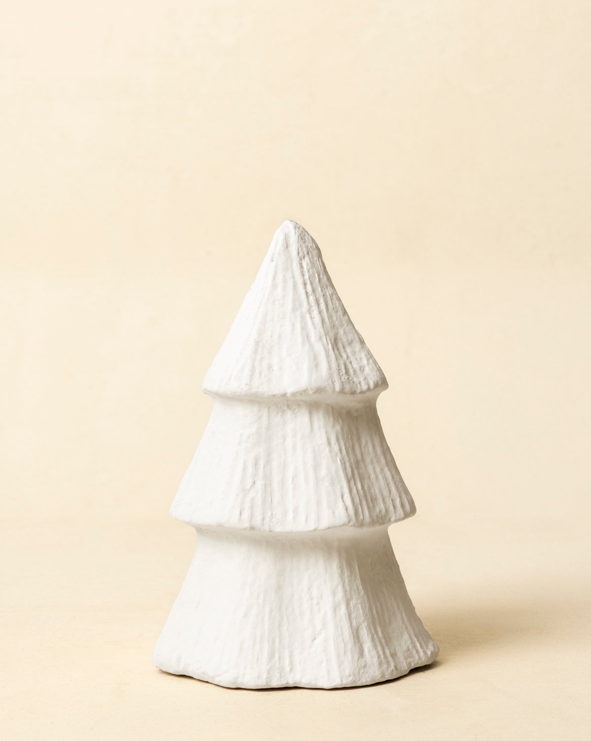 The Confectioners Paper Mache Tree is a small, white, handcrafted sculpture with three textured tiers, shaped like a stylized pine tree and ideal as elegant holiday décor on any neutral background, by Vendixs