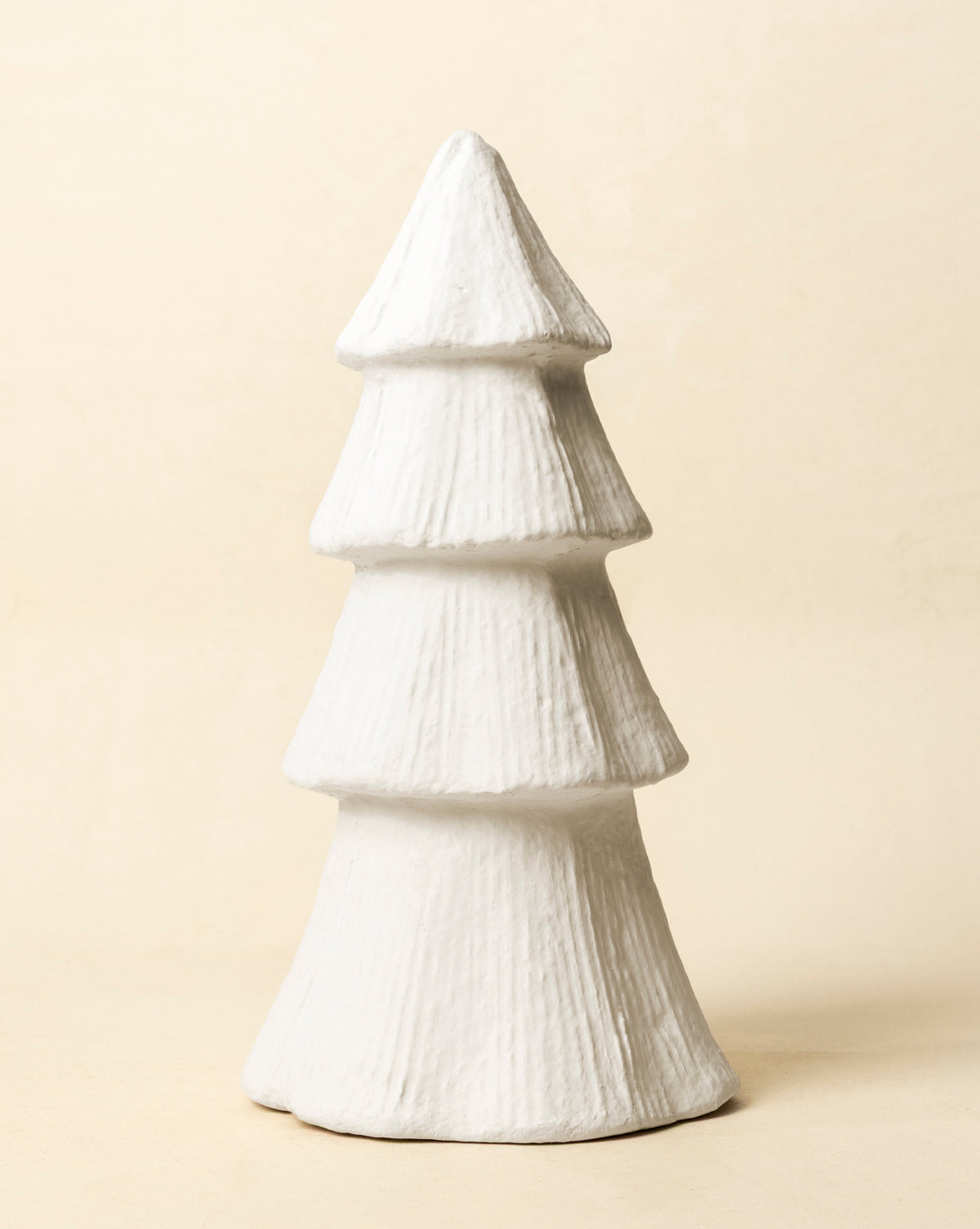 The Confectioners Paper Mache Tree is a handcrafted white, textured sculpture with three tiers, shaped like a stylized Christmas tree—perfect for adding festive décor to your space, by Vendixs