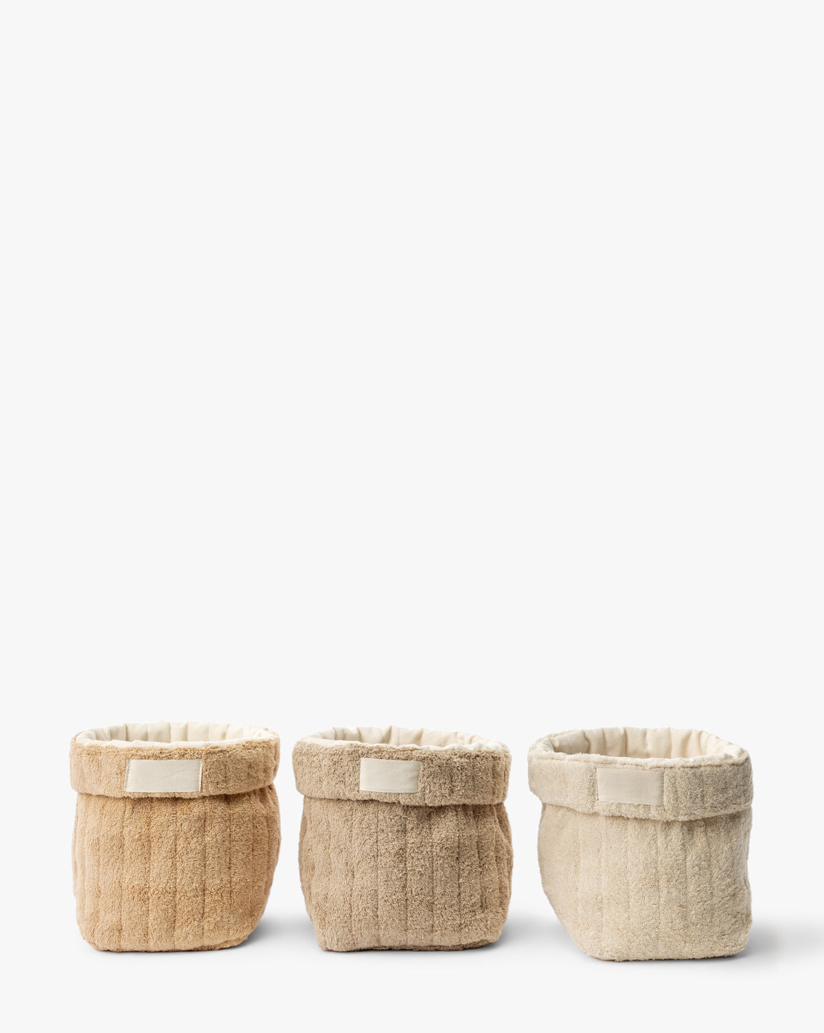 The Cotton Terry Cloth Baskets (Set of 3) in beige, light brown, and cream are neatly arranged side by side against a white background, providing a stylish way to organize your space, by Vendixs
