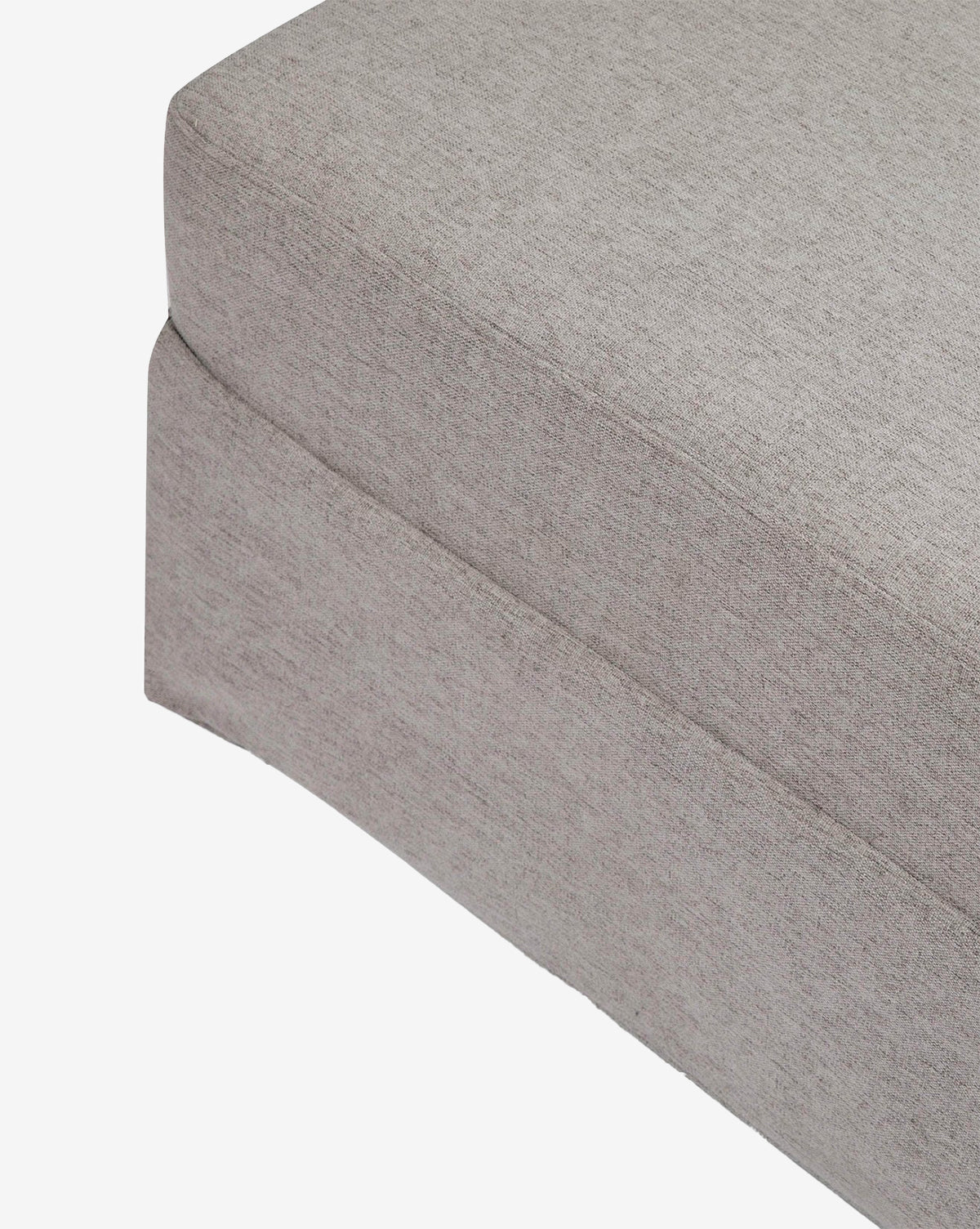 Close-up of the corner of a light gray Million Dollar Baby Crawford Gliding Ottoman cushion with a tailored skirt in eco-performance fabric, shown against a white background. Vendixs
