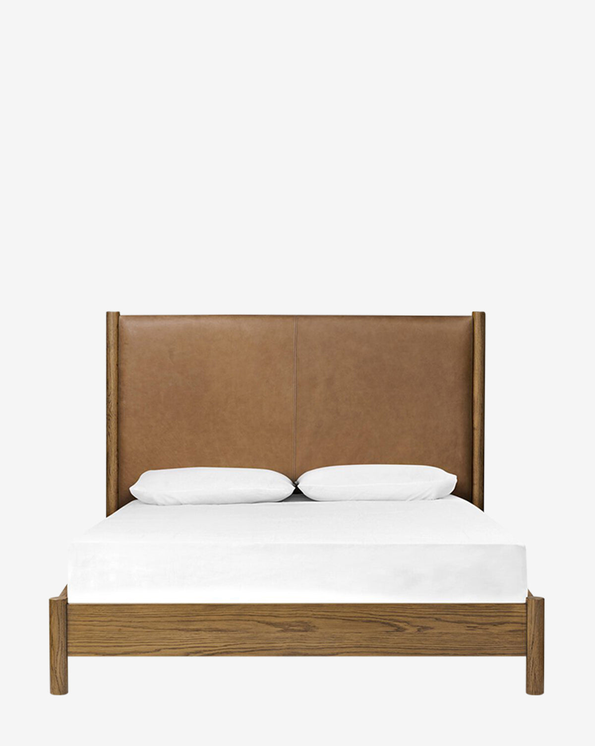 The Four Hands Crue Bed features a tall brown leather upholstered headboard, an oak frame, white bedding, and two white pillows, displayed against a plain white background. Vendixs