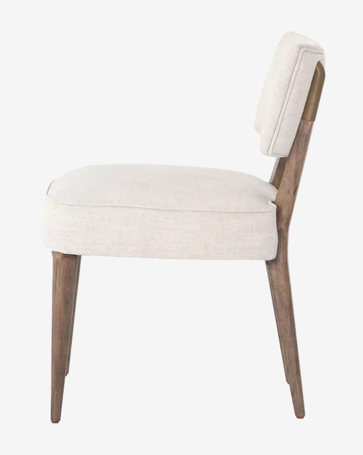 Side view of the Cyrene Dining Chair, showcasing its cushioned ivory performance fabric seat and backrest with four angled wood legs, all set against a plain white background by McGee & Co.