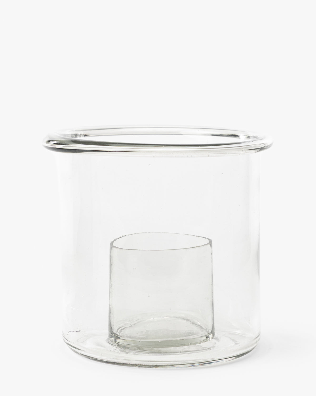 The Cyrus Hurricane is a clear glass candle holder with thick walls, a cylindrical shape, and an inner compartment at the base. Featuring a smooth wide rim, its perfect for stylish home decor by Vendixs