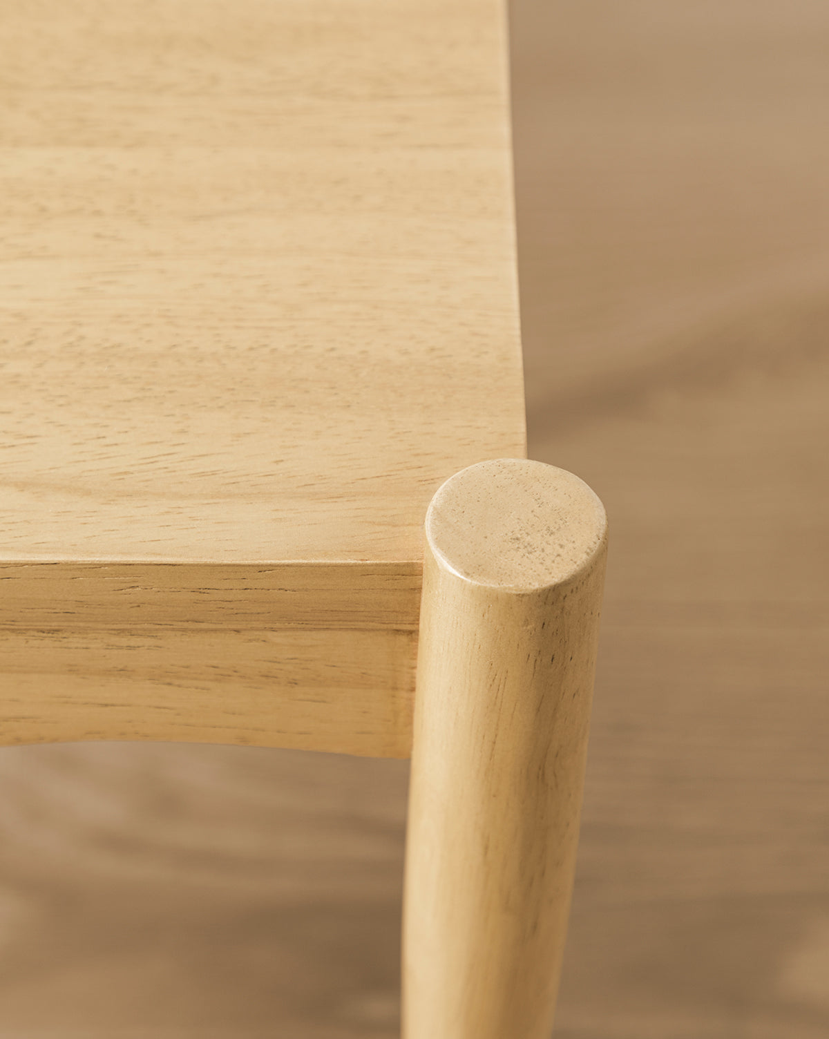 Close-up of a light wooden table’s smooth surface and rounded edge with one cylindrical leg—perfect to pair with the Darcy Kids Chairs (Set of 2) for a stylish childrens space, by Vendixs