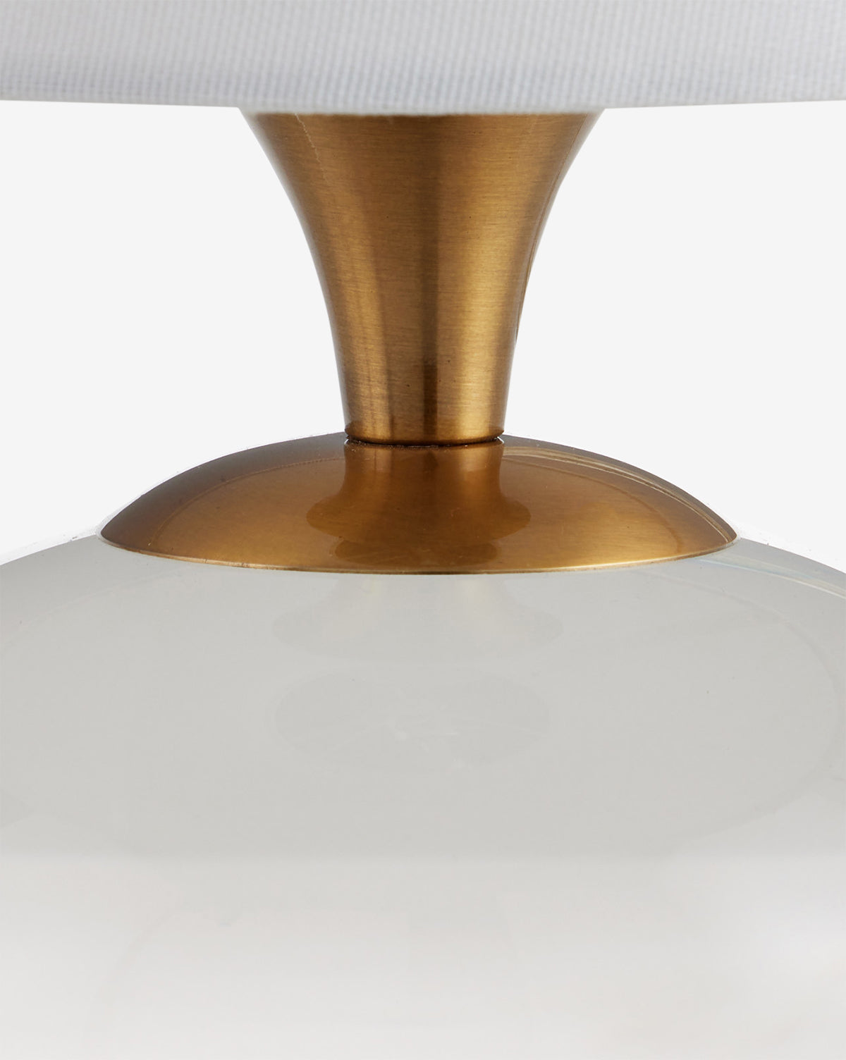 Close-up of the Diantha Table Lamp with an antique brass stem and base, a glossy white rounded body, and part of its white lampshade at the top, by Vendixs