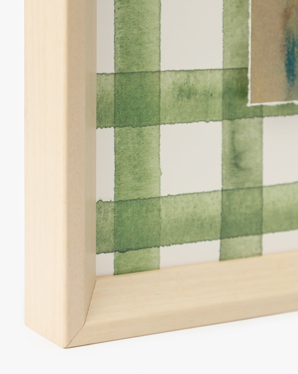 Close-up of a light wooden picture frame corner showcasing Dreamscape artwork—a green, watercolor-style plaid on watercolor paper—adding a fresh touch to your home decor, by Vendixs