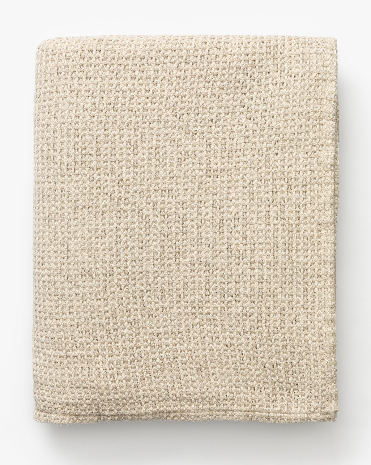The Penedo Duffy Oversized Throw, in beige waffle-knit fabric, sits neatly folded on a white background. Its textured pattern adds to the blanket’s cozy and soft look. Vendixs