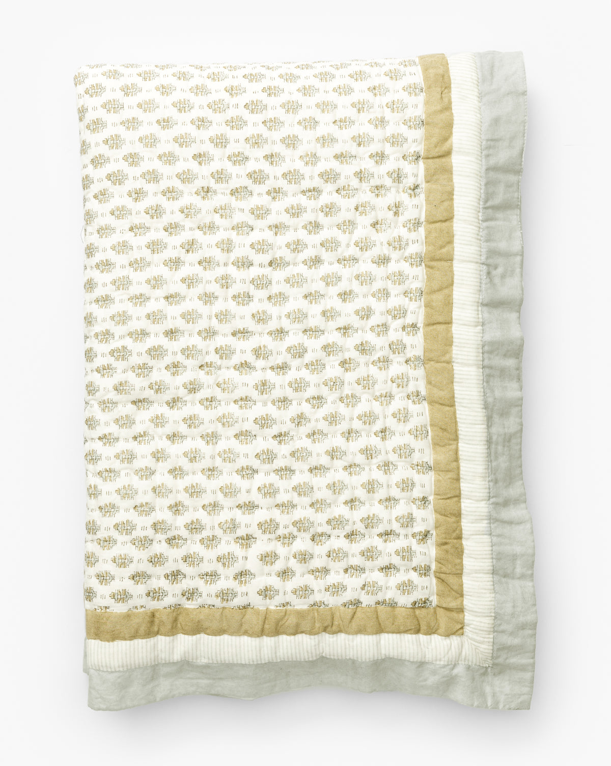 The Dulcie Block Print Kids Quilt by Renuka Inc. is folded to show its white center with small, light gold block print motifs, a solid gold border, and an outer white ruffled edge, all displayed on a white background. Vendixs