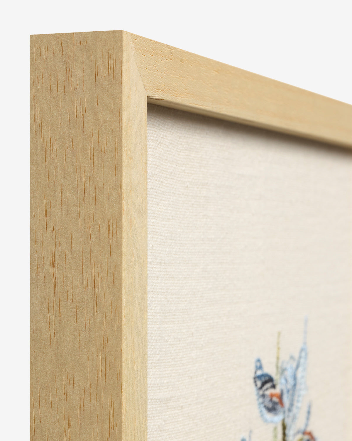 Close-up of a light wood frame with canvas, showcasing Embroidered Blue Iris—cotton embroidery of a blue and orange butterfly on cream, an elegant touch for your botanical wall art collection, by Vendixs