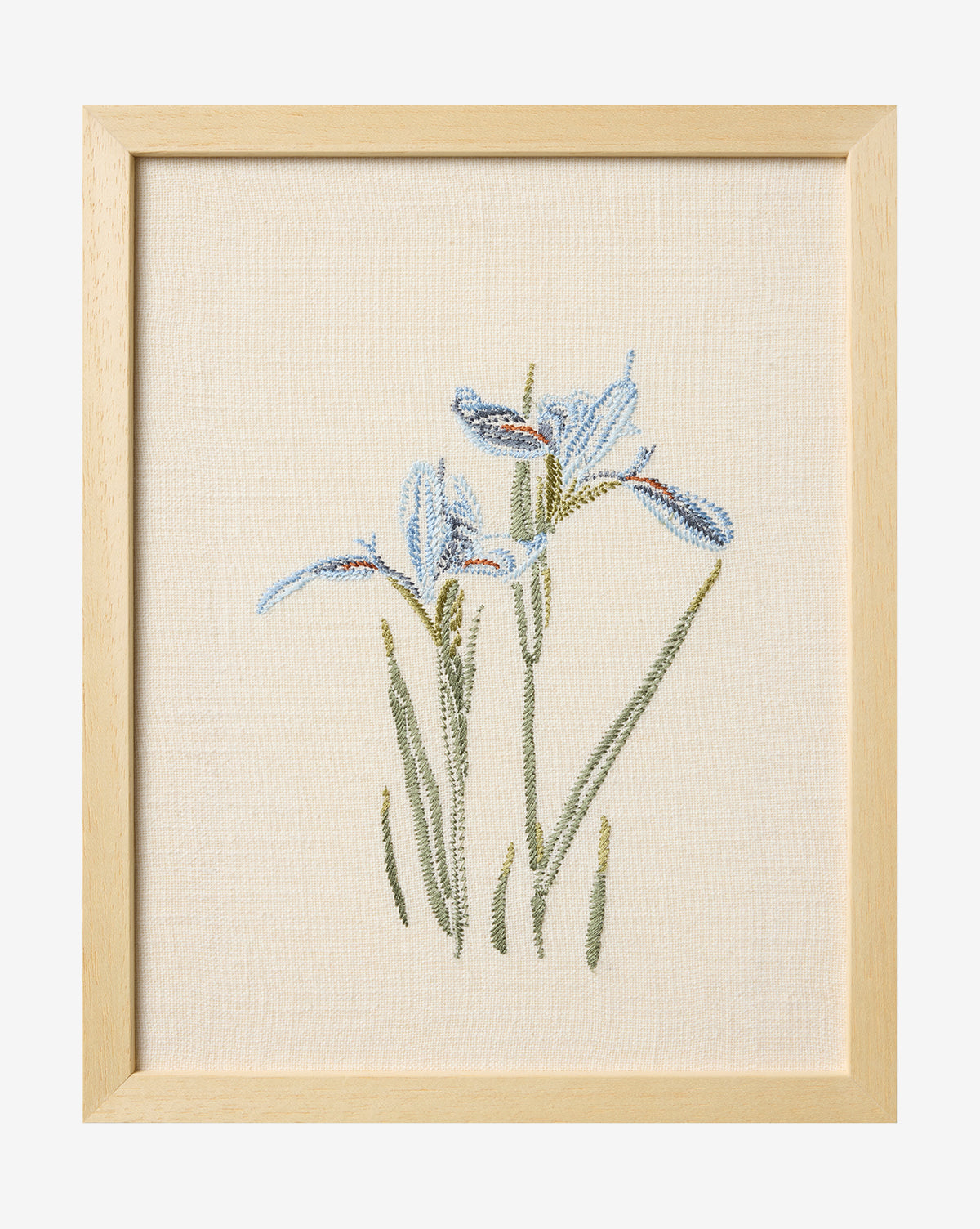 The Embroidered Blue Iris is a framed cotton artwork showcasing detailed blue irises with green stems on a cream fabric background—a gorgeous piece of botanical wall art, by McGee & Co.