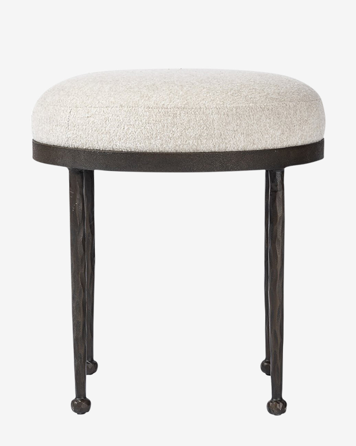 The Emmett Stool by Four Hands is a small, round accent piece with a cushioned light beige upholstered seat and three slender, textured black metal legs by Vendixs