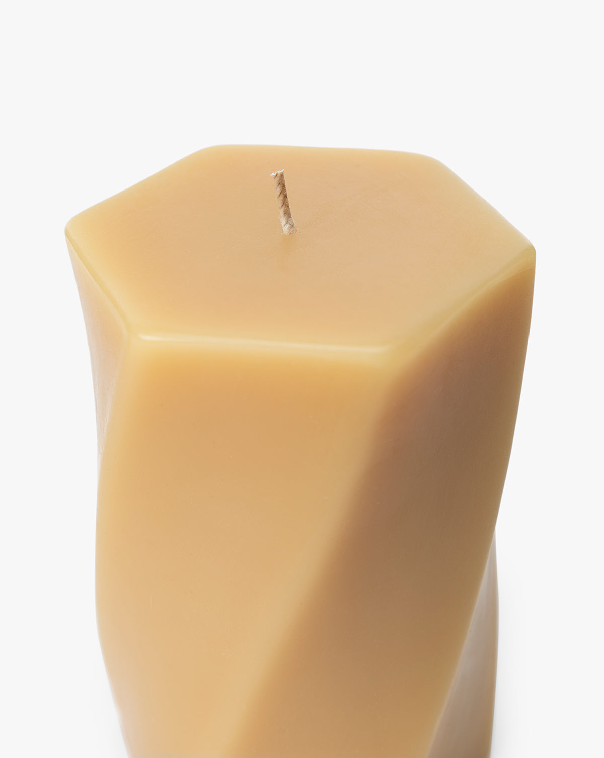 A close-up of the Errol Wax Pillar Candle, a beige modern piece with smooth, angled sides, geometric shape, and a single centered wick for a contemporary sculptural look, by Vendixs