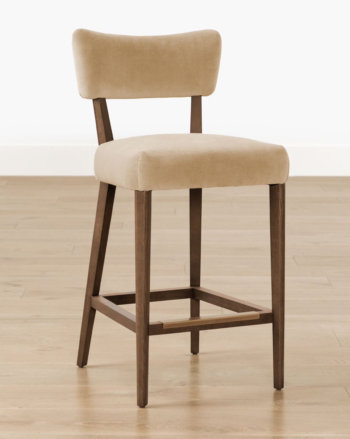 The Makerspalm Etienne Stool (Ready to Ship) features beige upholstery, a rectangular backrest and seat, wooden legs, and a footrest—ideal as a vintage-inspired accent for your kitchen or dining space. Vendixs