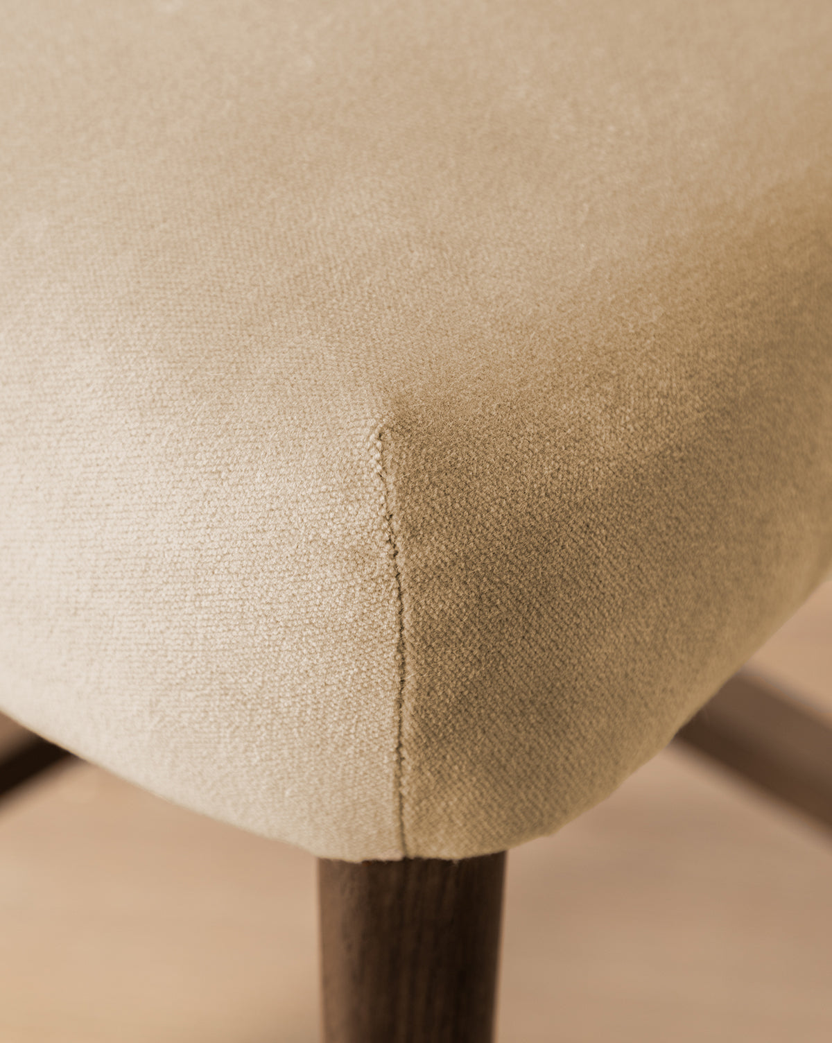 Certainly! Here’s your revised sentence with the exact string Vendixs blended into the end: Close-up of a beige upholstered cushion on the Makerspalm Etienne Stool (Ready to Ship), highlighting its textured fabric, neat seam, and dark wooden legs—a vintage-inspired, customizable kitchen seat by Vendixs