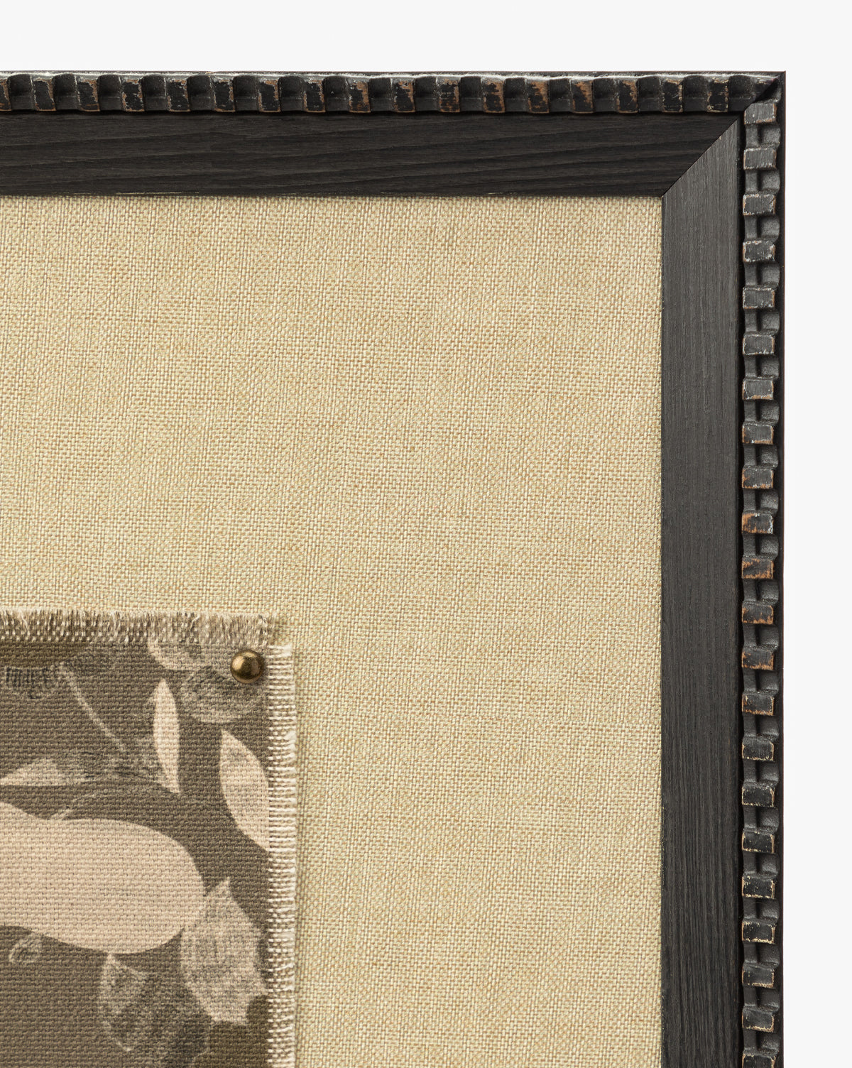 A close-up of the Fable textural art piece on beige fabric in a dark wooden frame, with a pinned fabric swatch featuring a neutral leaf and floral design by Vendixs