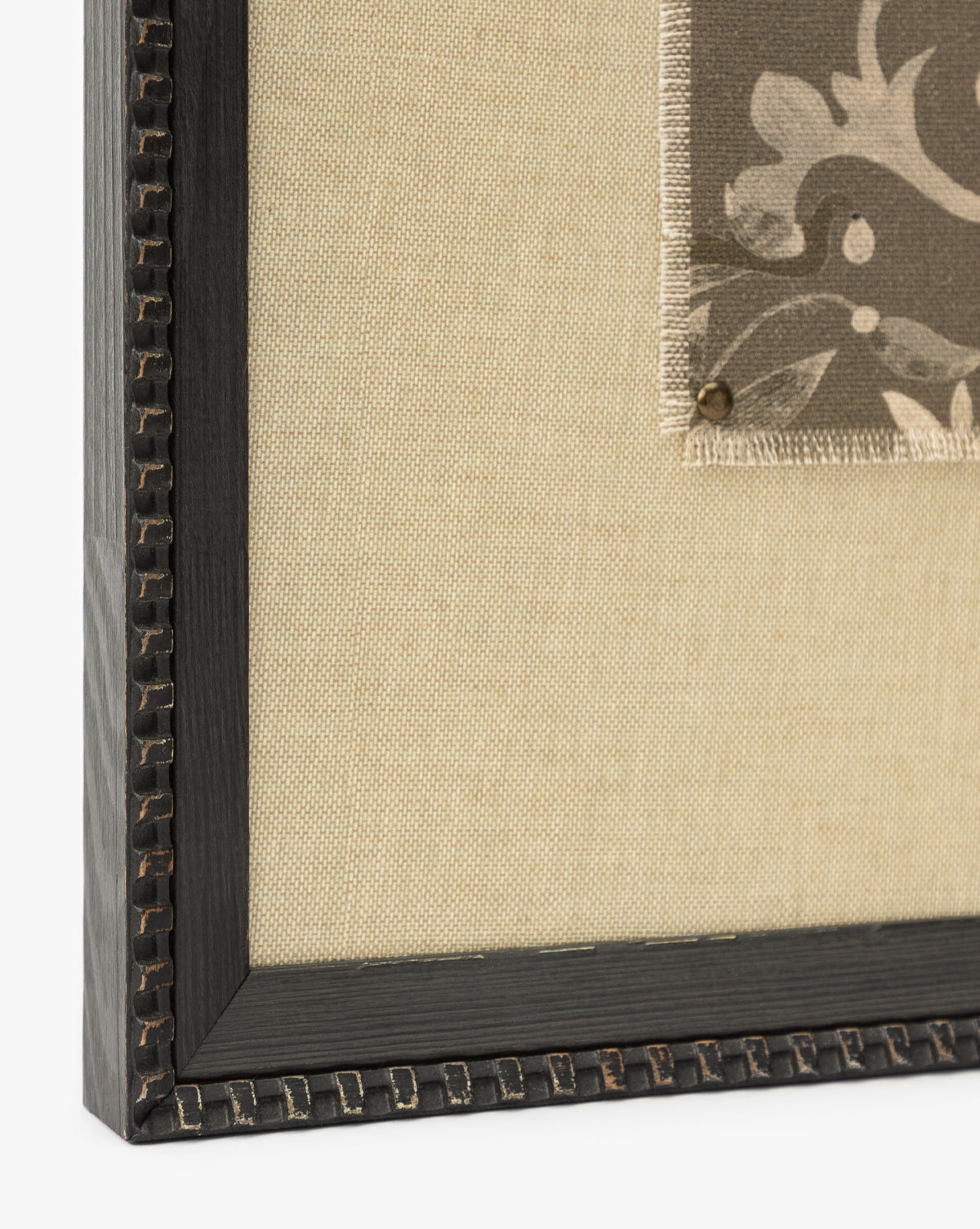 Close-up of Fable, a textural art piece with a dark decorative black frame, beige fabric background, and a small patterned fabric swatch pinned to the right by Vendixs