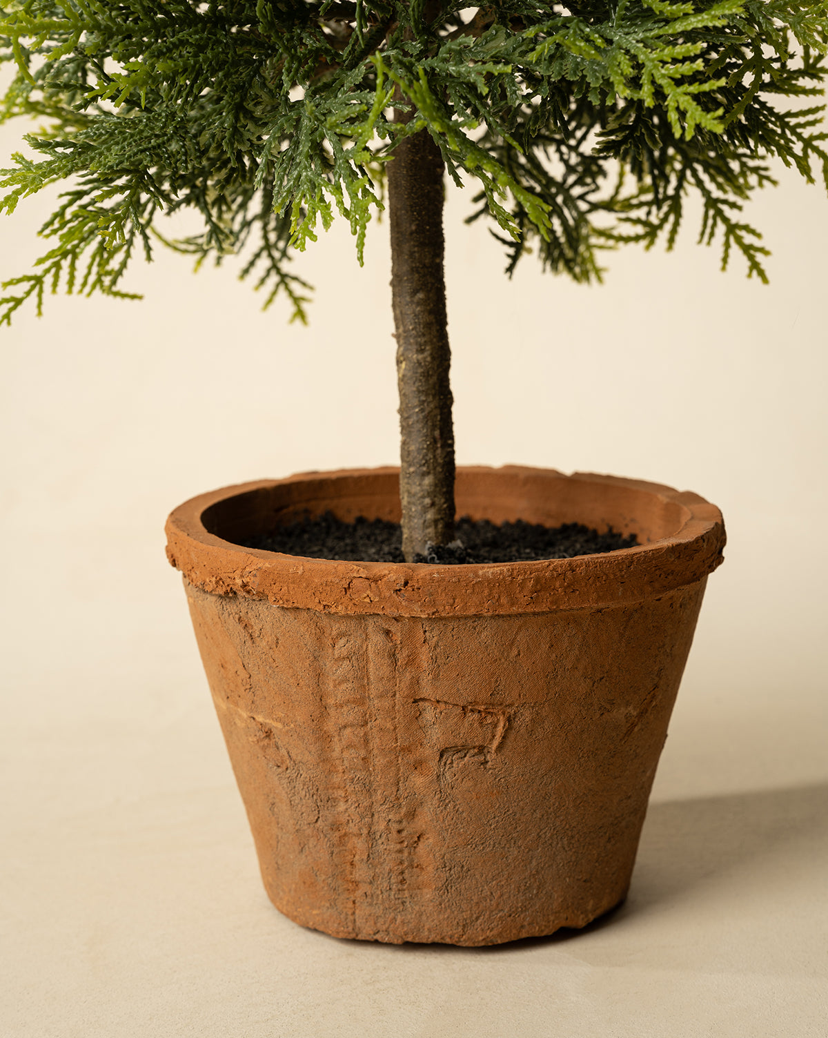 The 15.5" Cypress Faux Potted Topiary features green needle-like leaves in a round, textured terracotta pot with dark soil, set against a light, neutral background, by Vendixs