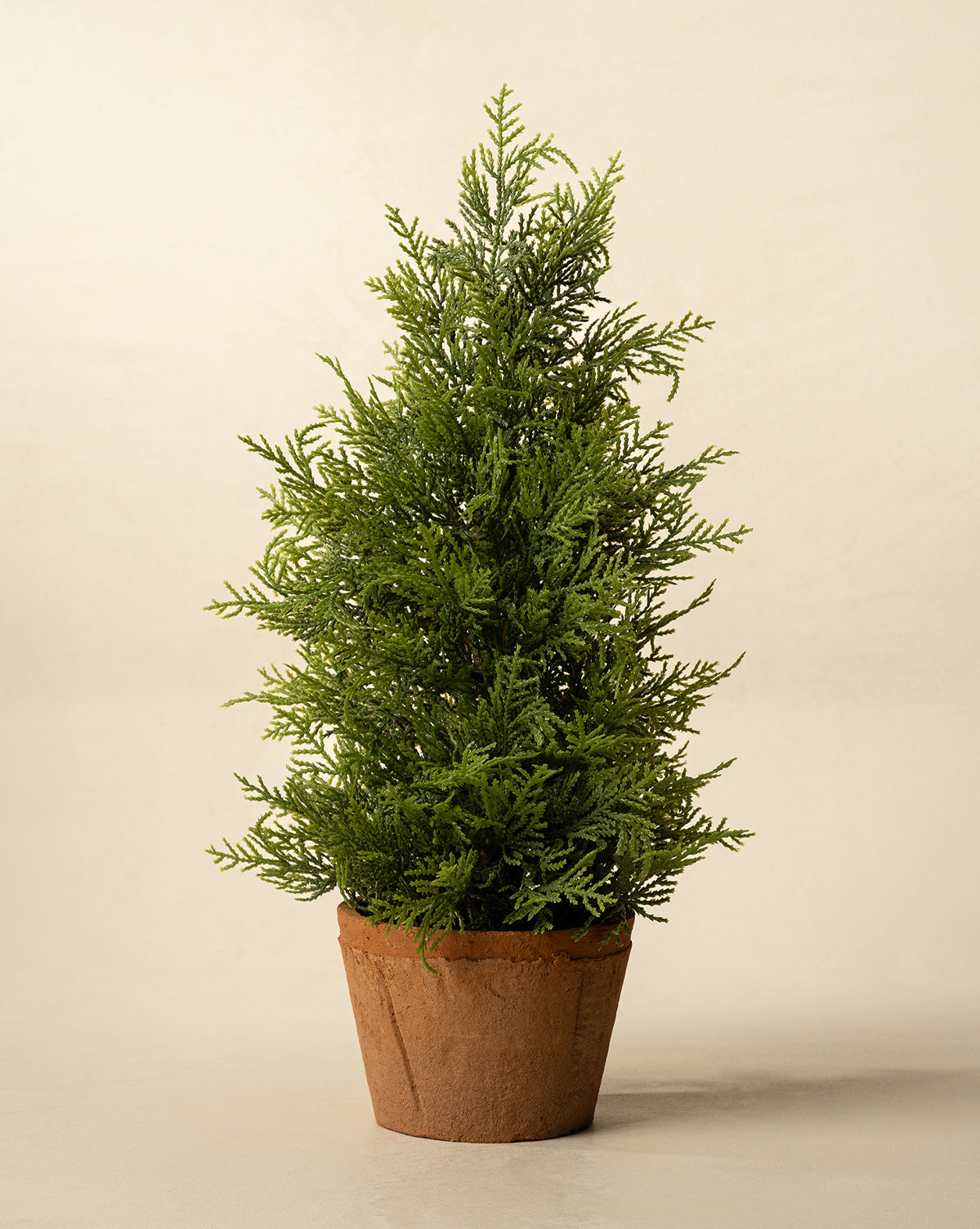 The 17" Cypress Faux Potted Tree features dense, needle-like green foliage and comes in a terracotta pot, perfect for adding a touch of greenery to any room, by Vendixs