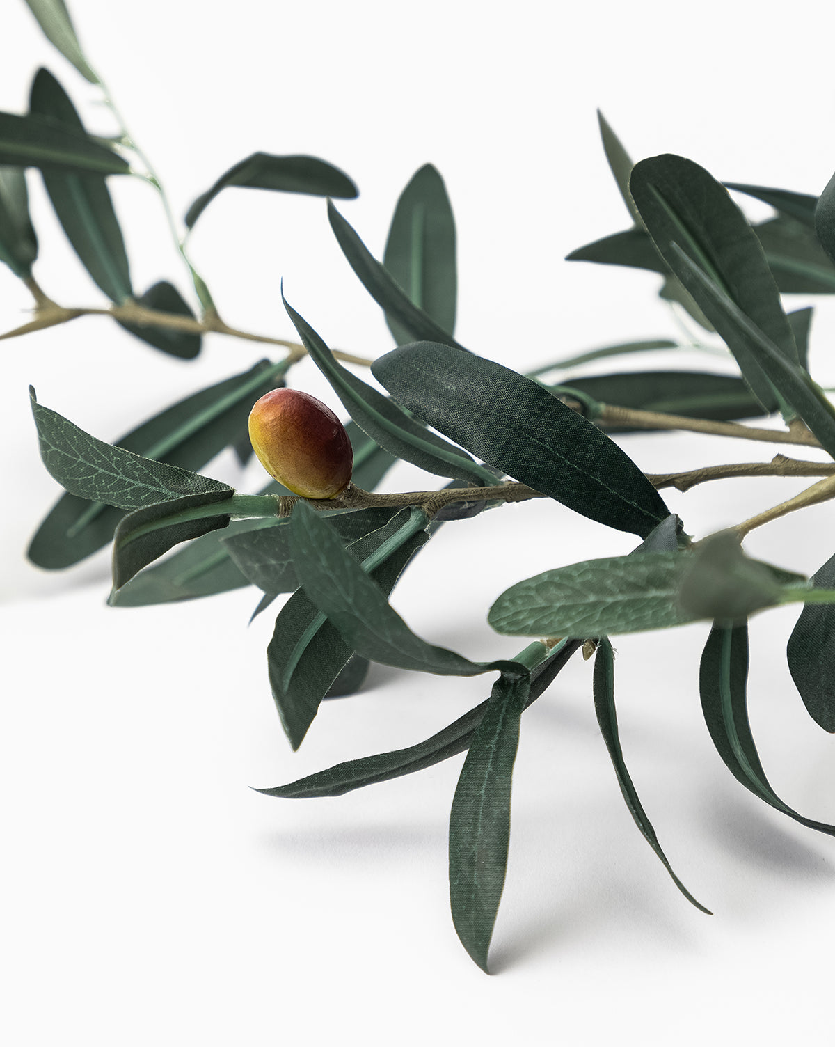 A close-up of the Faux Olive Branch, featuring dark green leaves and a single ripe olive against a white background—ideal for olive branch decor, by Vendixs