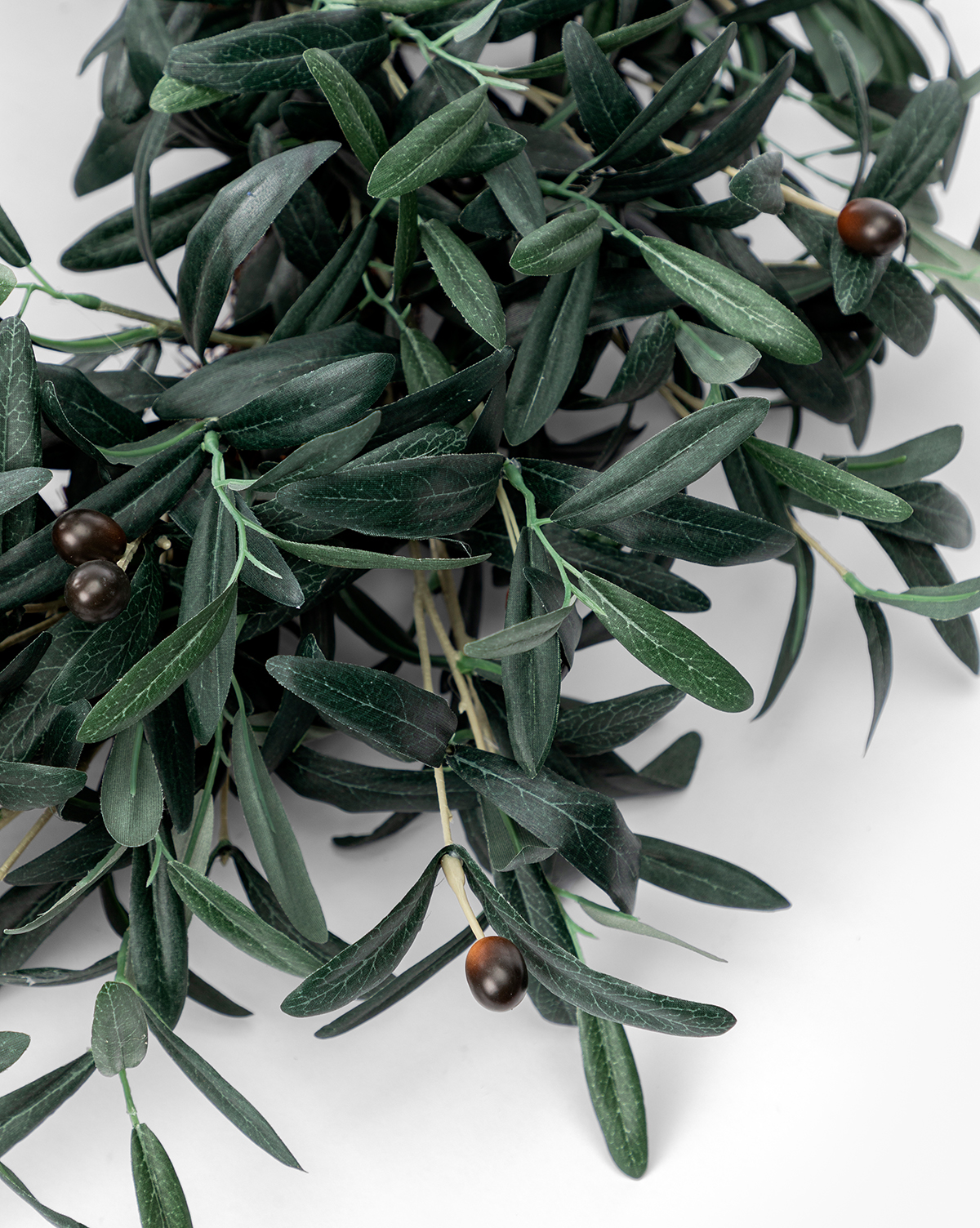 A close-up of the Faux Olive Berry Wreath, displaying lifelike green olive branches and dark olives on a white background. The long, narrow leaves and realistic berries range in color from dark brown to black, by Vendixs