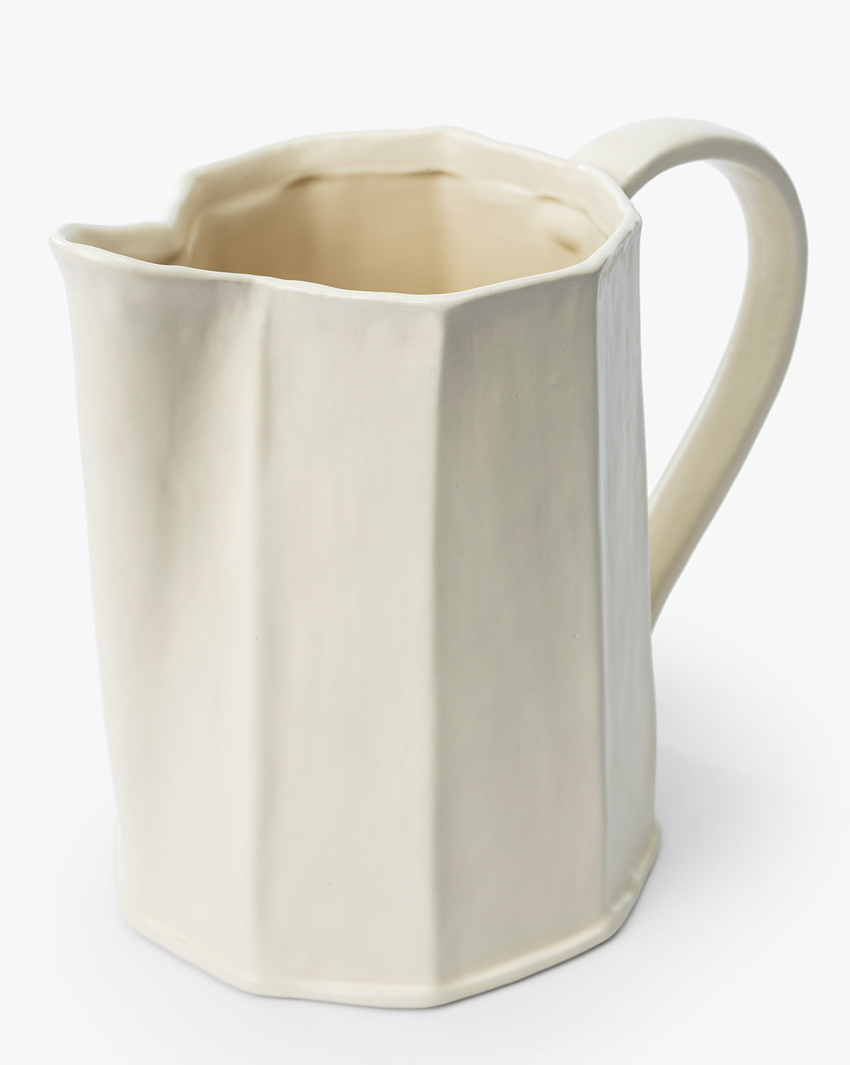 The Fielding Ceramic Pitcher is a cream-colored stoneware piece with a faceted, angular design and curved handle, ideal for rustic kitchen decor, photographed against a plain white background by Vendixs