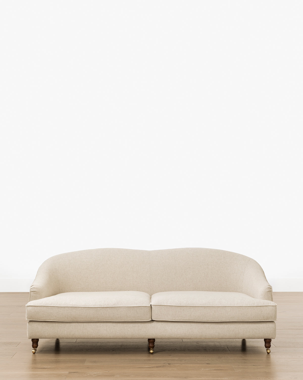 The Makerspalm Fletcher Sofa 76 (Ready to Ship) features a beige upholstered finish, curved backrest, and wooden legs. It sits on a light wood floor against a plain white wall, adding handcrafted, customizable style to any space by Vendixs