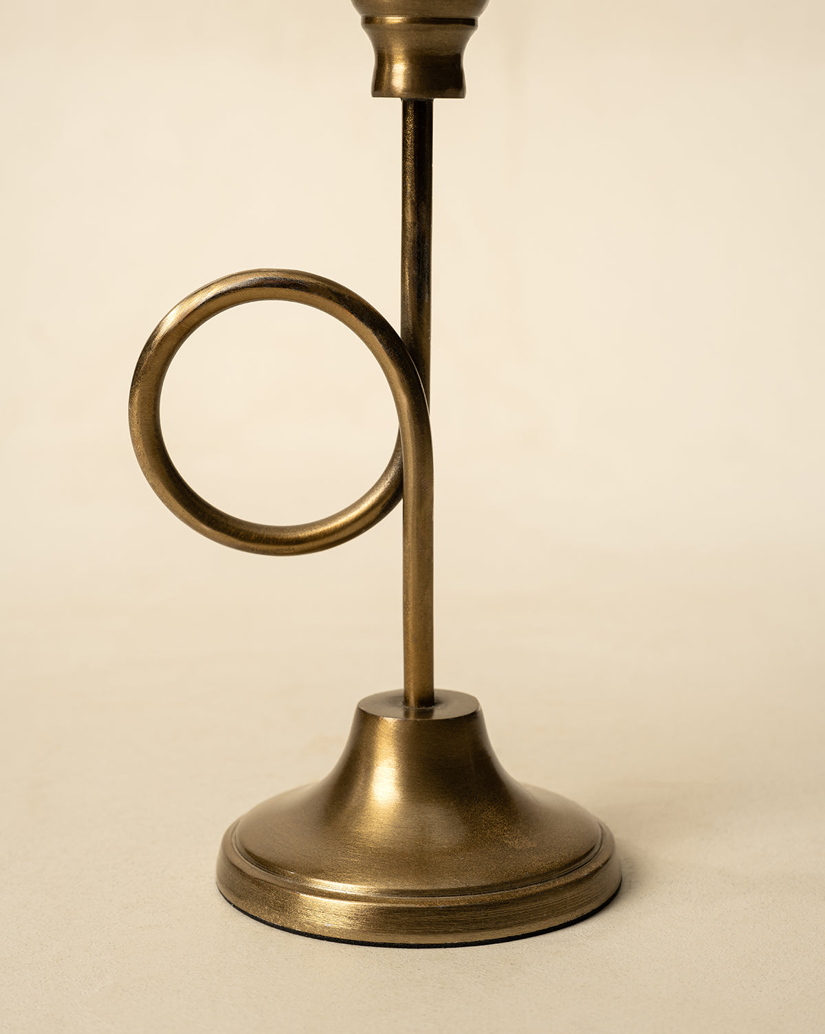 The French Horn Taper Holder, crafted from brass with a circular loop stem detail, is ideal for holiday styling and displayed on a simple light background, by McGee & Co.