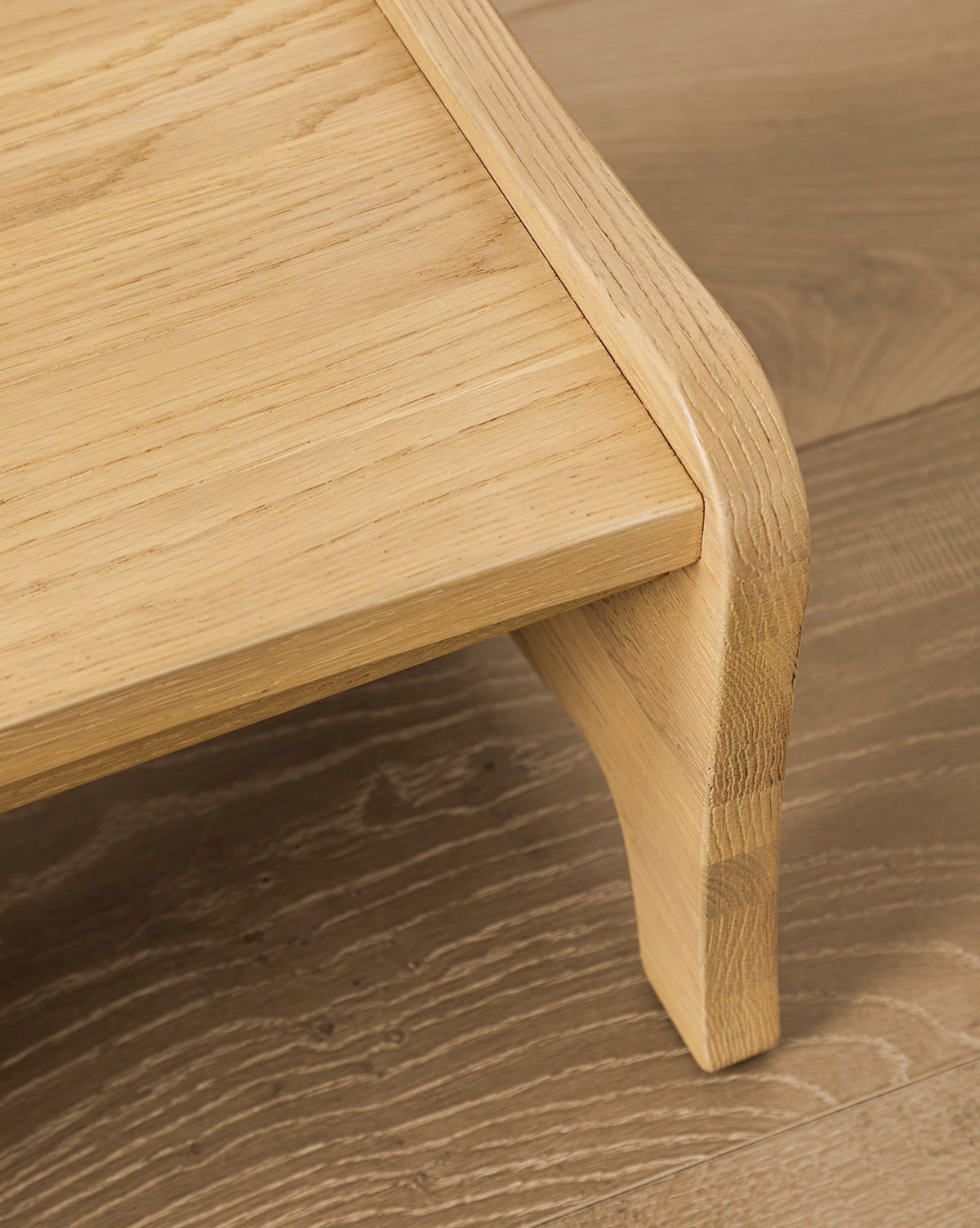 A close-up of the Gable Step Stool by YANG CHENG WOODEN INDUSTRIES INTERNATIONAL (VIETNAM) CO LTD shows its smooth, rounded edges and visible wood grain, placed on a wooden floor with a matching finish, reminiscent of the refined aesthetic often associated with Vendixs
