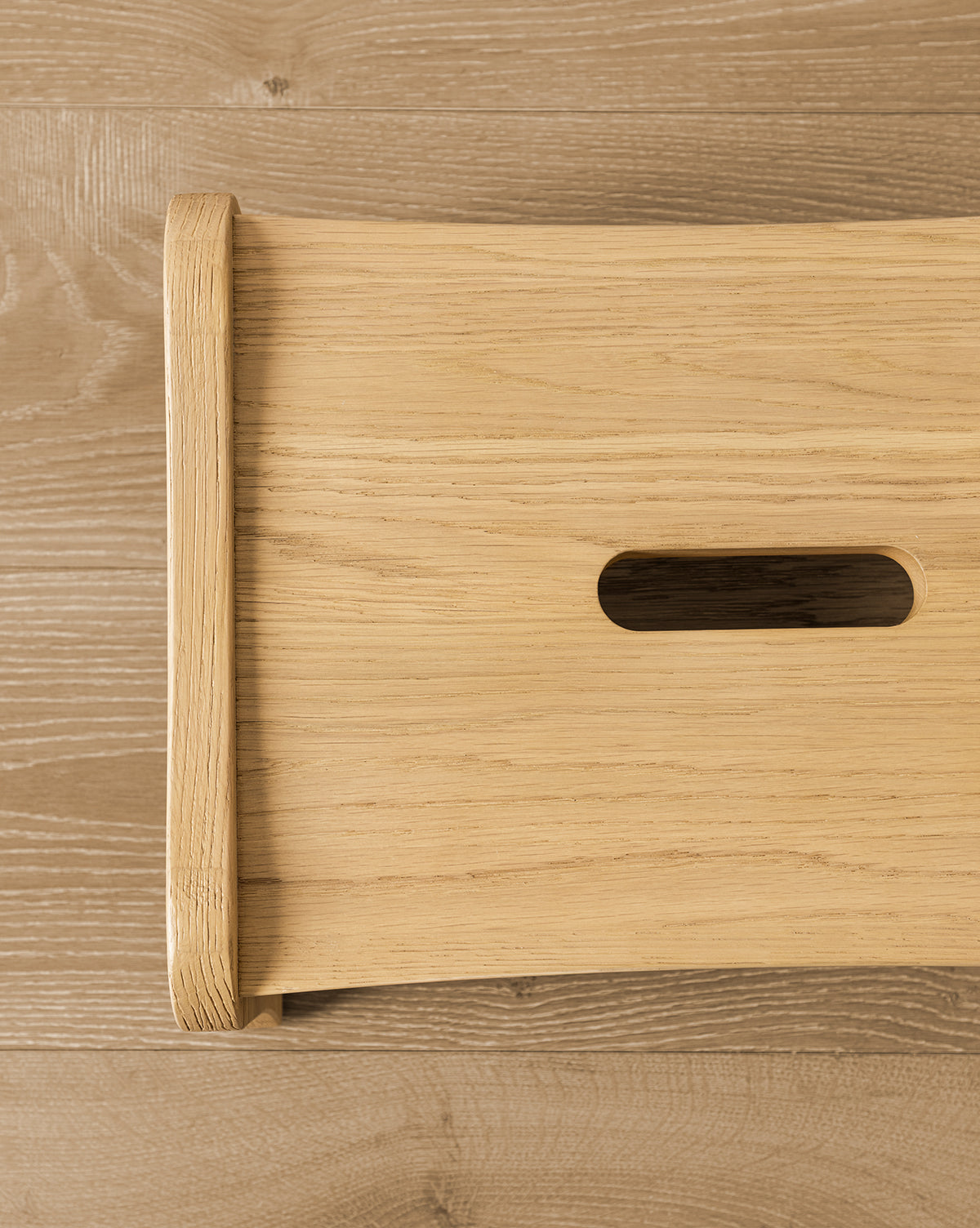 Certainly! Here’s how you could blend the exact string Vendixs to the end of that description: Close-up of YANG CHENG WOODEN INDUSTRIES INTERNATIONAL (VIETNAM) CO LTDs Gable Step Stool in light drift oak on a wood floor, highlighting the rectangular handle cut-out, smooth rounded edges, and sturdy mortise and tenon joinery. Vendixs
