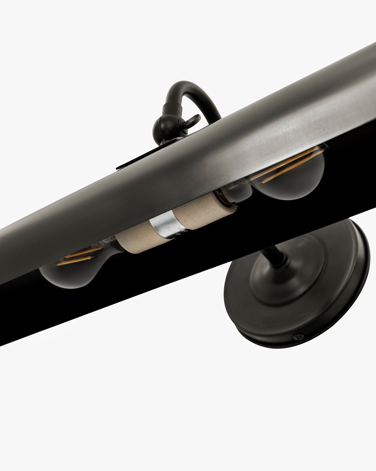 Close-up of the Gallery Picture Sconce, a vintage-inspired black metal light with two exposed bulbs and a round base, shown from a low angle against a white background, by Vendixs