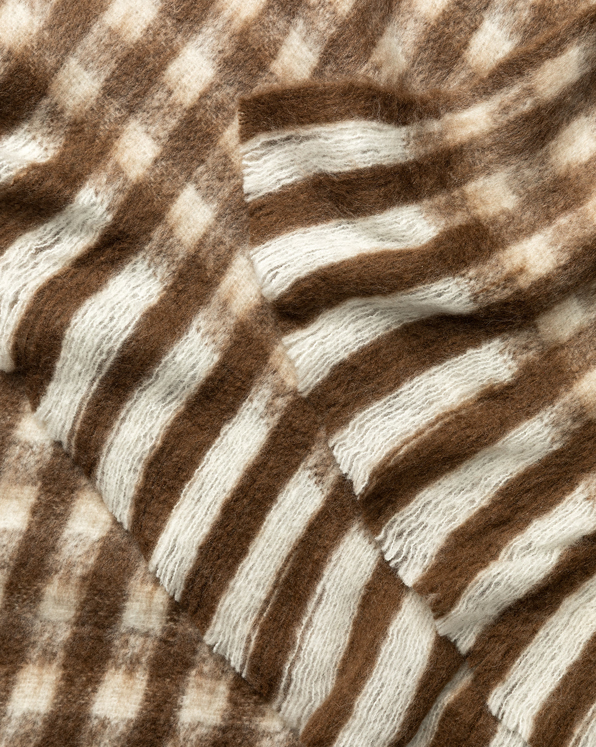 Close-up of the Indaba Gingham Wool Blend Throw, featuring soft, fuzzy fabric with brown and white horizontal stripes arranged in overlapping layers for a cozy, textured look. Vendixs