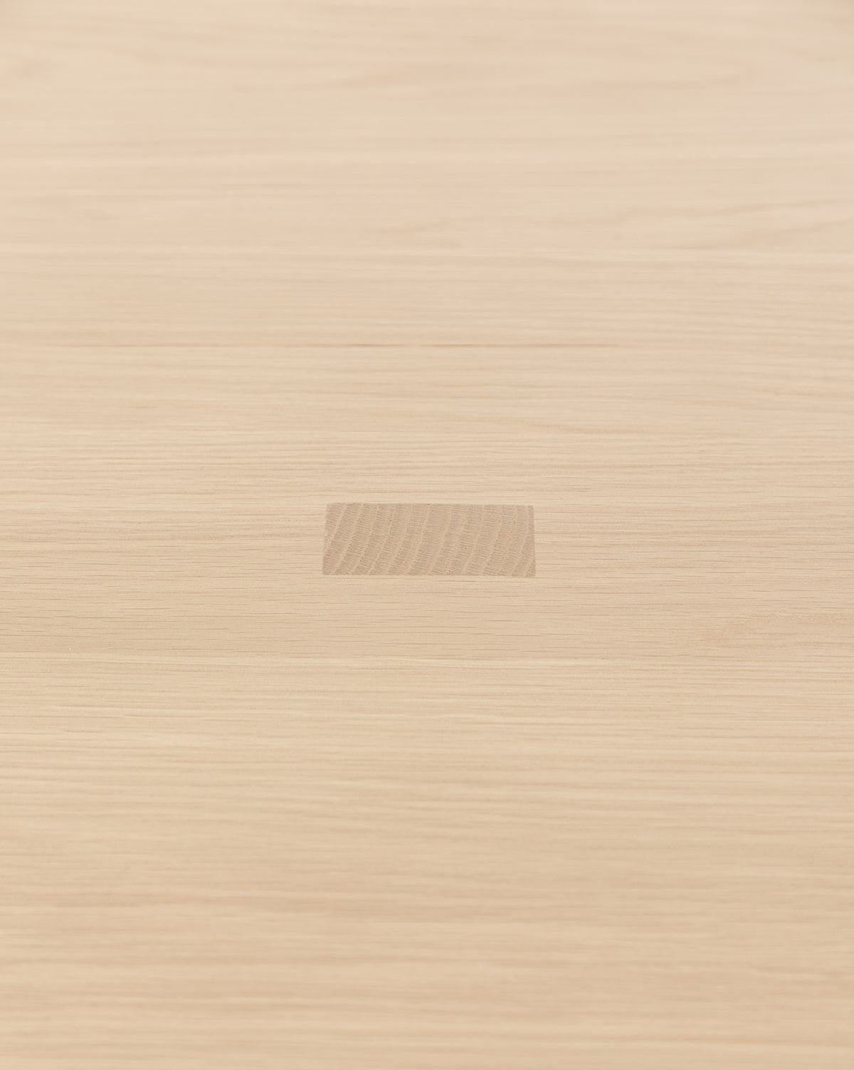 The Giselle Oval Dining Table features a light wood surface reminiscent of white oak, with a central rectangular patch where the wood grain subtly differs from the rest of the tabletop, by McGee & Co.