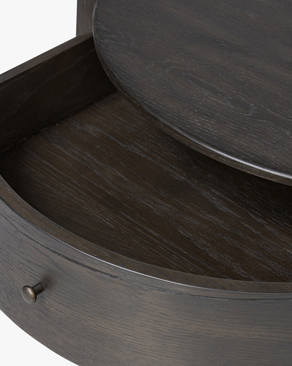 Close-up of the Glenndon Oak Nightstand’s black-finished drawer with an open rounded front, showcasing the wood grain texture and a metallic knob handle on the left side, by Vendixs