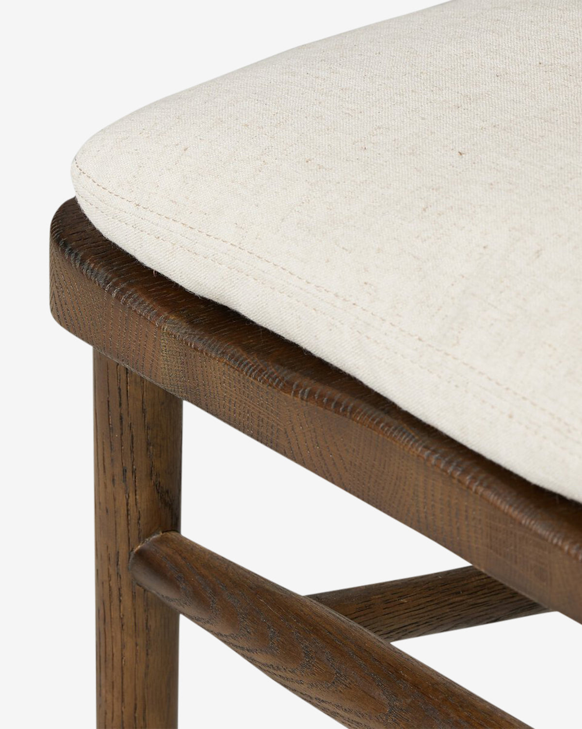 Close-up of the Hallow Chair, a rustic dining chair with a dark brown finish, beige upholstered cushion, and visible wood grain on the frame and crossbar, by Vendixs