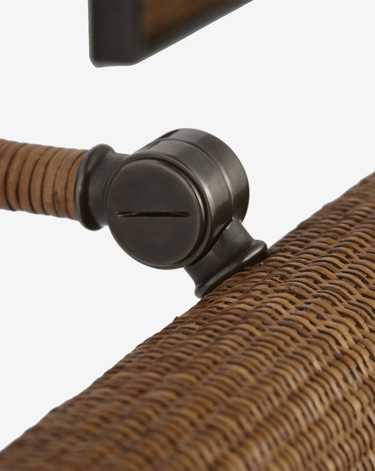 Close-up of the Halwell Picture Light: a black metal adjustable clamp attached to a brown woven rattan chair frame, ideal for securing artwork or picture lighting, featuring a wrapped detail on the arm, by Vendixs