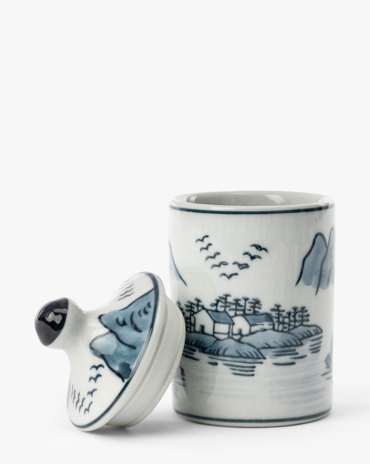 The Hand-Painted Spice Jars (Set of 4) feature blue and white scenic landscapes with trees, mountains, birds, and water. Each ceramic jar includes a lid that can be removed to reveal the open top—perfect as unique artisanal kitchen decor by Vendixs
