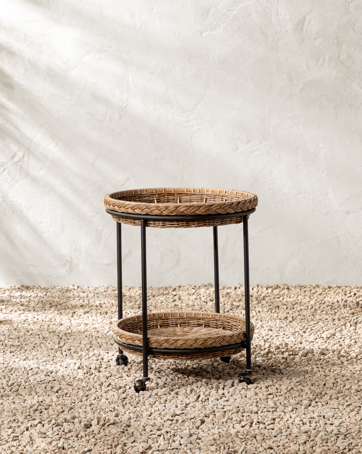 Set on a pebble floor by a textured white wall, sunlight casts soft shadows—ideal for stylish outdoor entertaining, by McGee & Co.