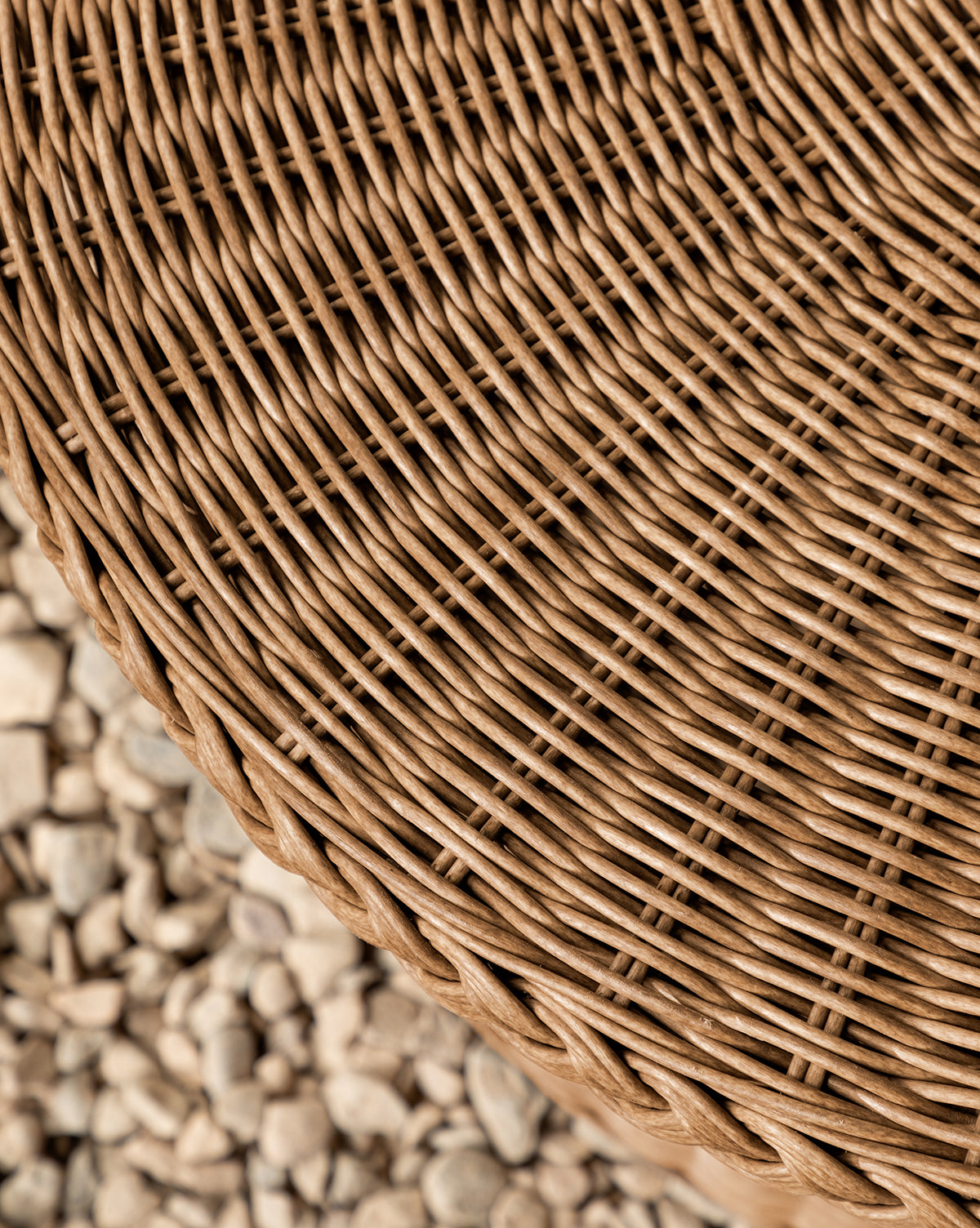 Close-up of the Haviland Coffee Table, featuring weather-resistant, tightly woven light brown wicker, set against a backdrop of small, light-colored pebbles, by Vendixs