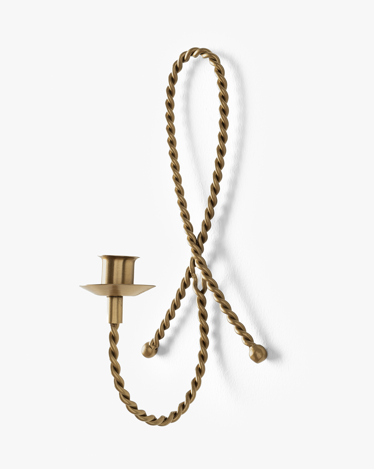 The Hearst Taper Holder is a brass candle holder with a twisted, rope-like loop that mounts to the wall at two points, featuring an elegant taper extension from the lower left side, by Vendixs