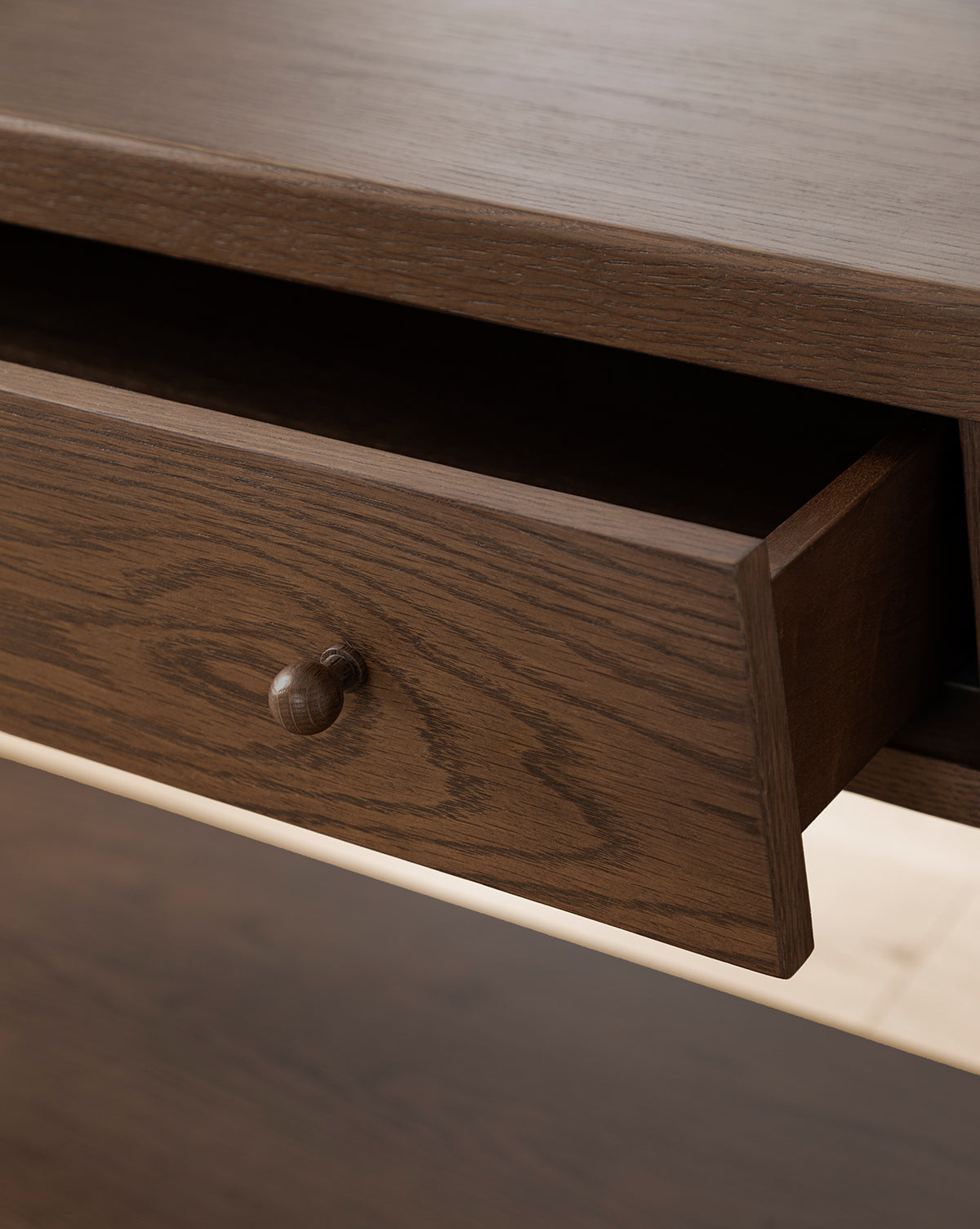 A close-up of the Heathcliff Console shows a partially open wooden drawer, featuring a round wooden knob and distinct wood grain patterns on its two-drawer design, by Vendixs