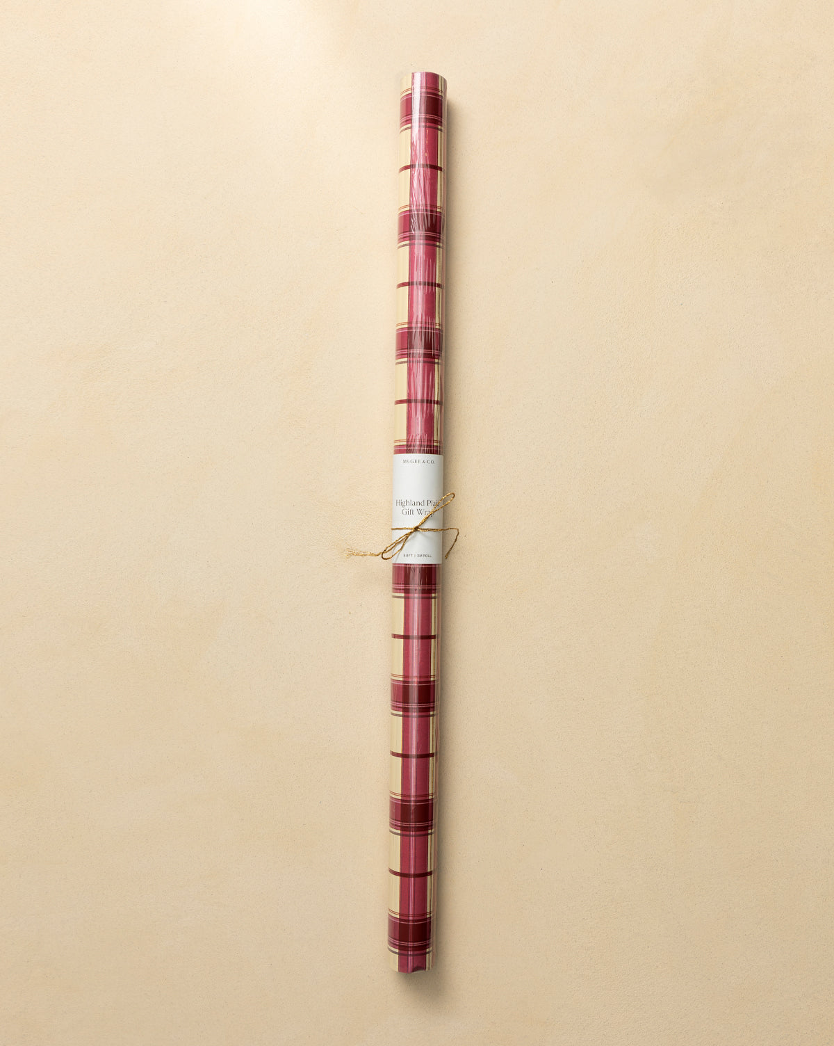 Highland Plaid Gift Wrap in red and gold with a white label and twine, set on a light beige background—ideal festive wrapping paper for the holidays, by Vendixs